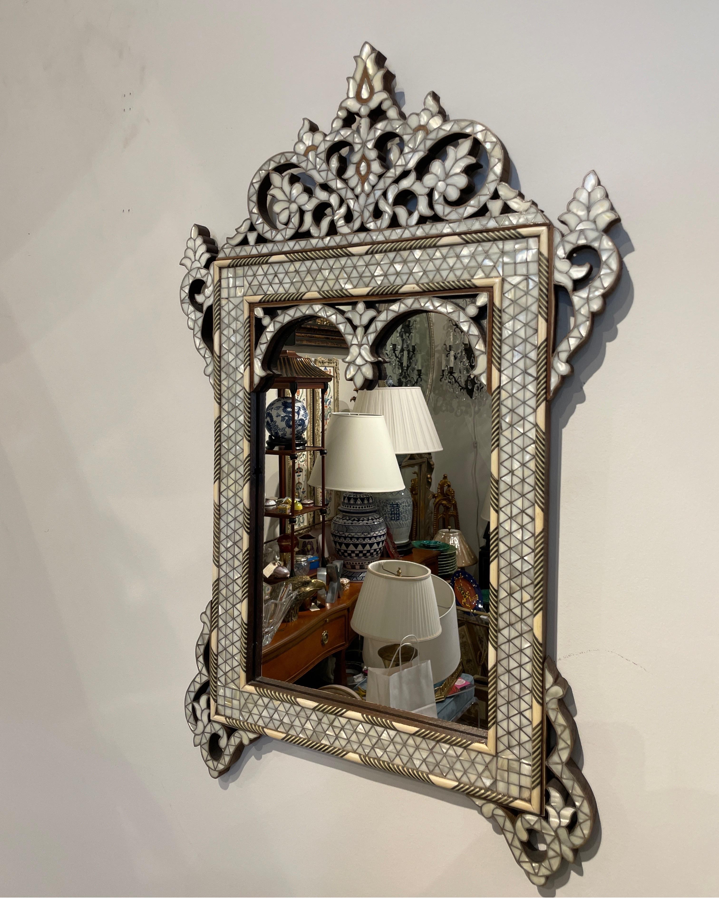 Beautifully detailed mother of pearl & bone inlaid mirror. This elegant mirror with attached pediment & side adornments would look great in a powder room or almost any other place you choose to use it. Very fine quality.