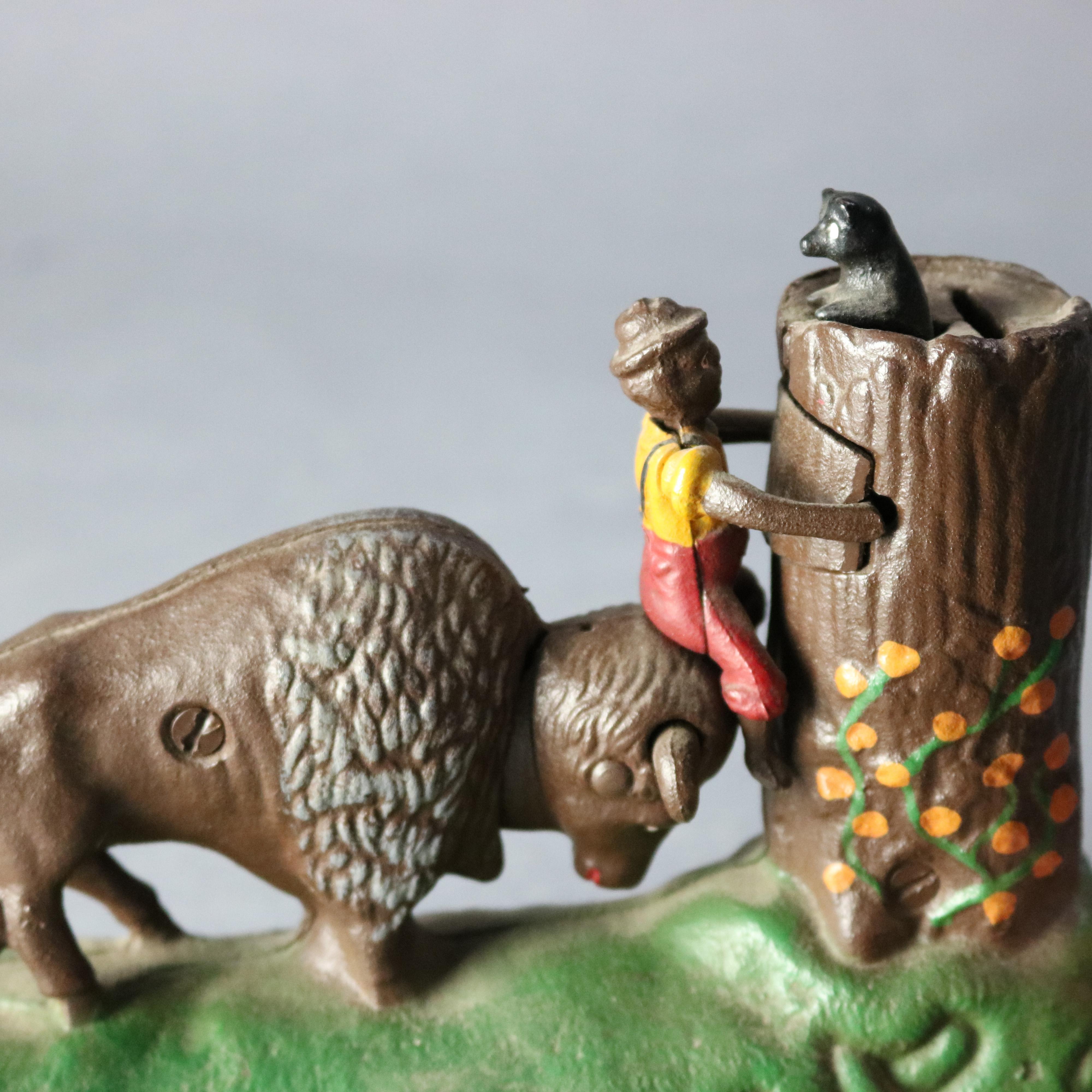 A vintage Book of Knowledge Butting Buffalo mechanical bank offers polychrome cast construction with buffalo, figure, tree and squirrel, underside reads 