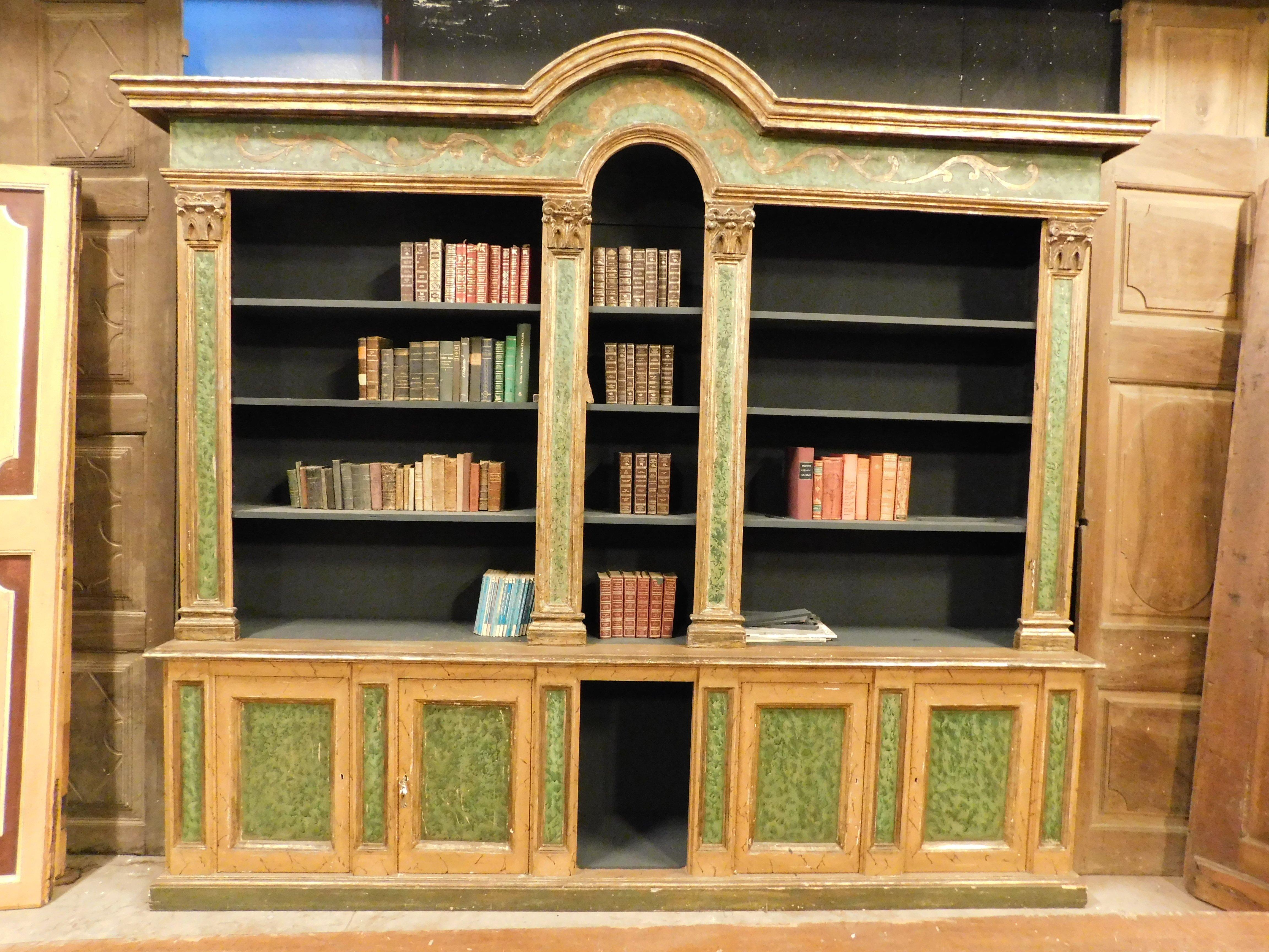 Vintage Bookcase in lacquered and gilded wood, with painted faux green marble and gold-finished molure, built in the 1950s in Italy.
It has a base with closed doors and open shelves, very spacious and in good condition, redone simulating the