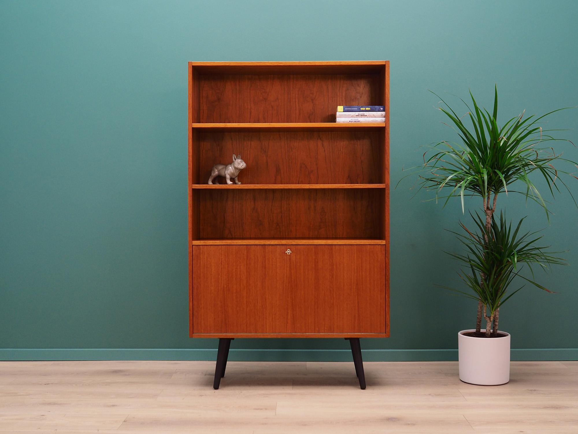 Fantastic bookcase from the 1960s-1970s. Scandinavian design, Minimalist form. Surface of the furniture finished with teak veneer. Bookcase has two shelves and a practical bar. Preserved in good condition (minor bruises and scratches) - directly for
