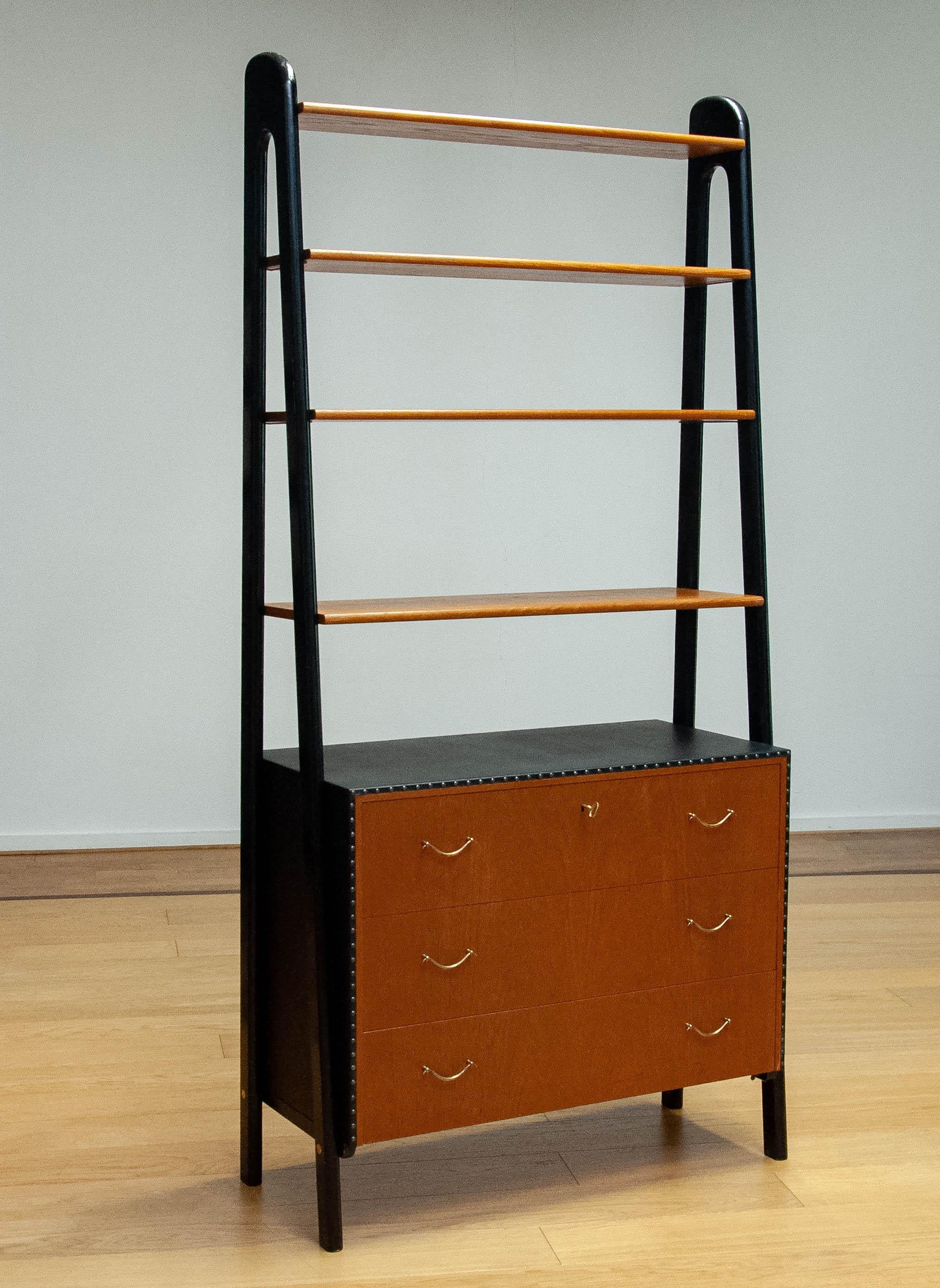Beautiful and very decorative Scandinavian bookcase cabinet designed by Bertil Fridhagen and made by SMF Svenska Möbelfabriken Bodafors In Sweden in the 1950s.
The cabinet consists three with teak veneered drawers which top drawer can be locked. All
