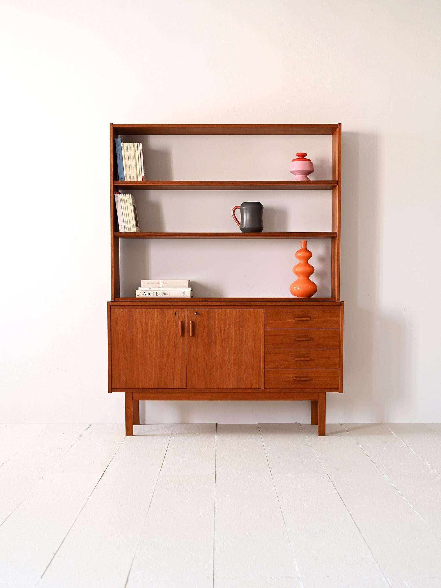 1960s teak cabinet with shelving and writing desk.

A simple and functional piece of furniture consisting of a sideboard with hinged doors and 4 drawers on which rests a frame with shelving. 
The essential lines are enriched by some details such as