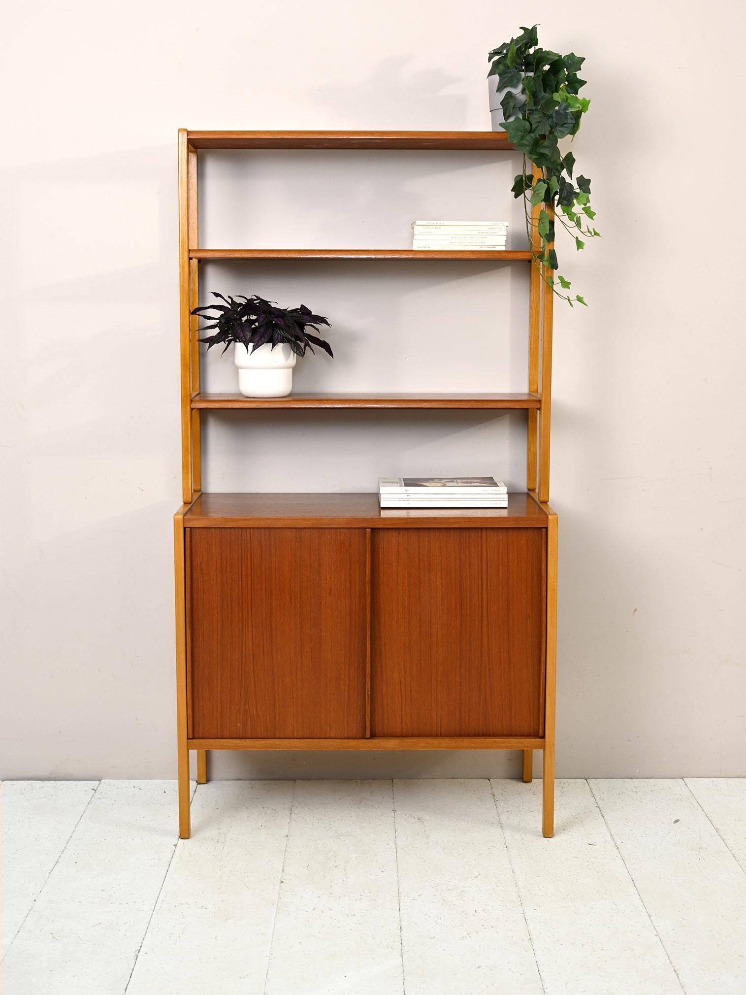 Original Scandinavian teak cabinet consisting of two parts.
The upper part is a bookcase equipped with adjustable height shelves, the lower part is a storage cabinet with sliding doors. 
Despite its small size it turns out to be practical and