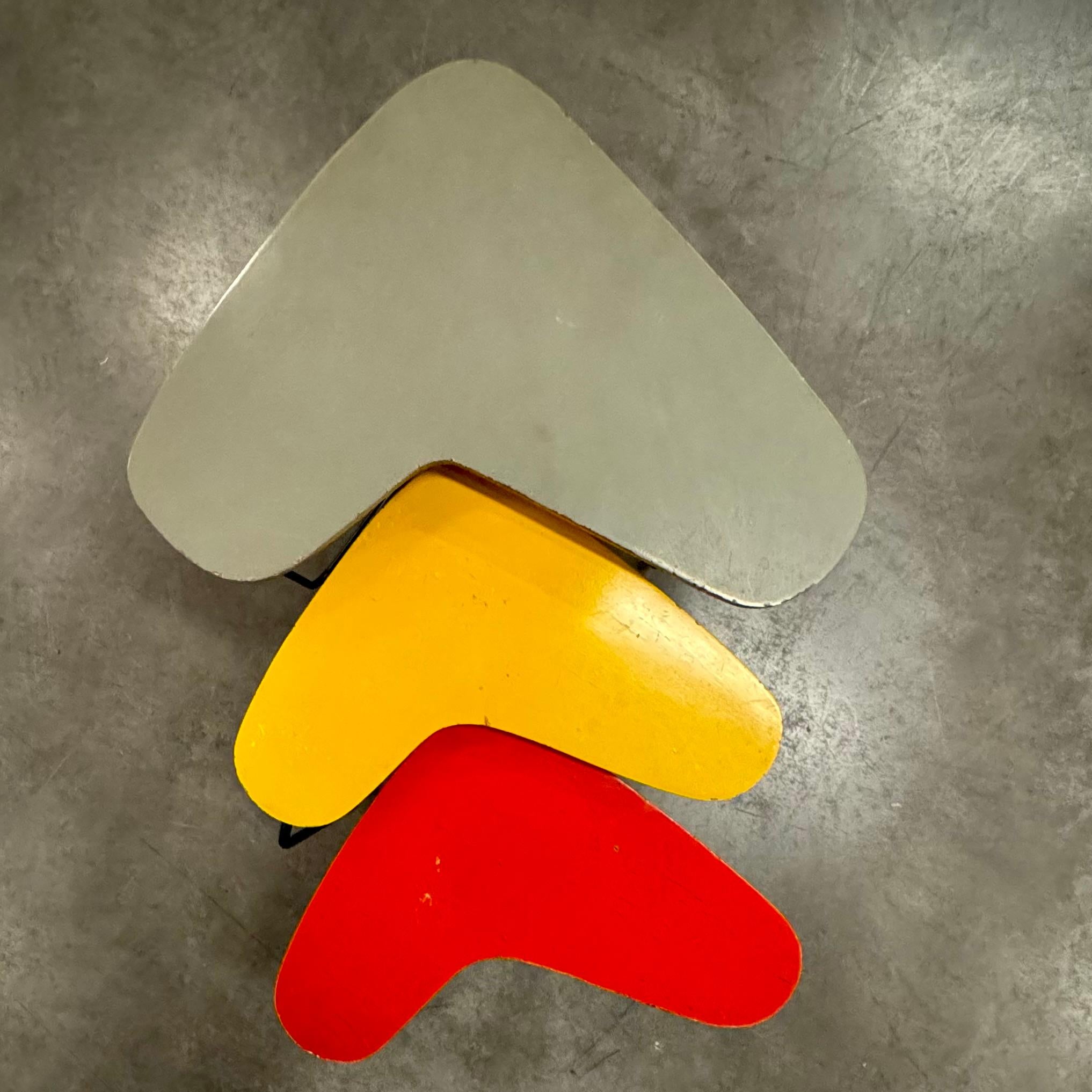 This captivating set of three nesting tables showcases the iconic boomerang shape, a hallmark of mid-century design. Crafted by Belgian architect and furniture designer Willy Van Der Meeren in 1953, these tables feature grey, yellow and red