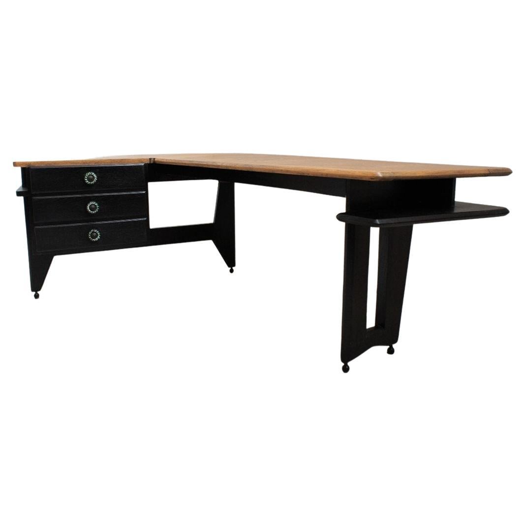 Rare boomerang desk by Guillerme and Chambron. This late 50s desk is a sculptural piece of design and features a double patina; ebony for the lower part, natural oak for the writing table, the storage drawers are decorated with ceramic handles by