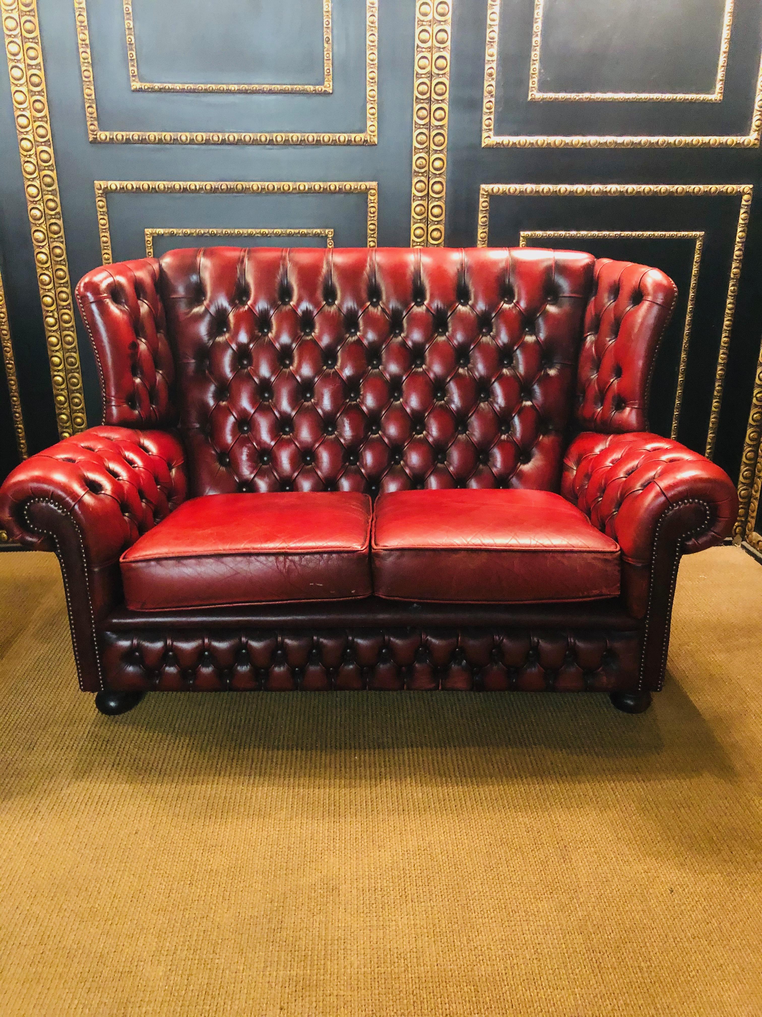 Beautifully aged English Chesterfield wingback seater or sofa. Featuring a tufted cordovan leather upholstery English rolled arms.
 