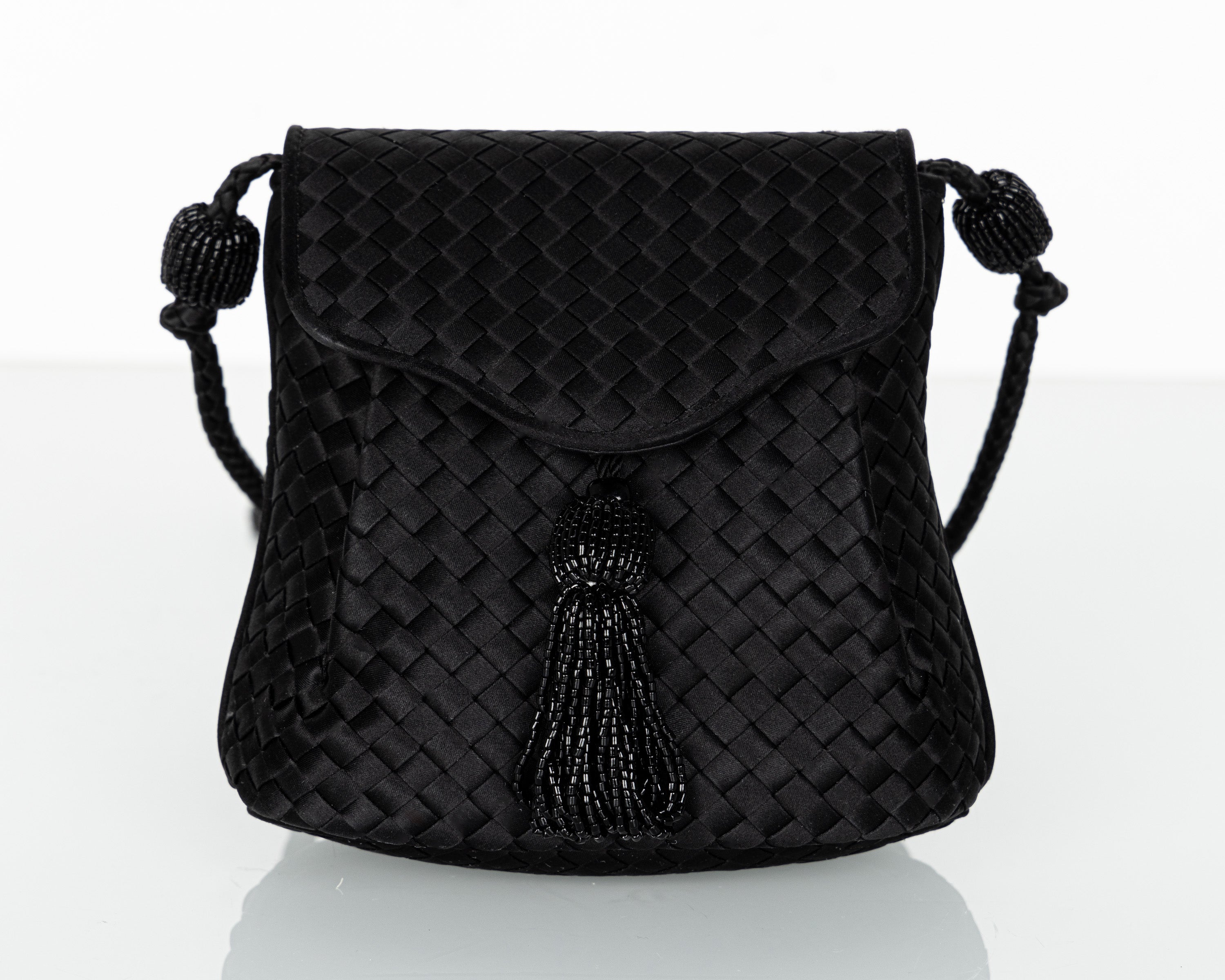 This extraordinary Bottega bag captures the essence of vintage luxury, showcasing the unmatched craftsmanship and attention to detail for which Bottega Veneta is renowned. Crafted from lustrous black satin, this bag features the iconic intrecciato