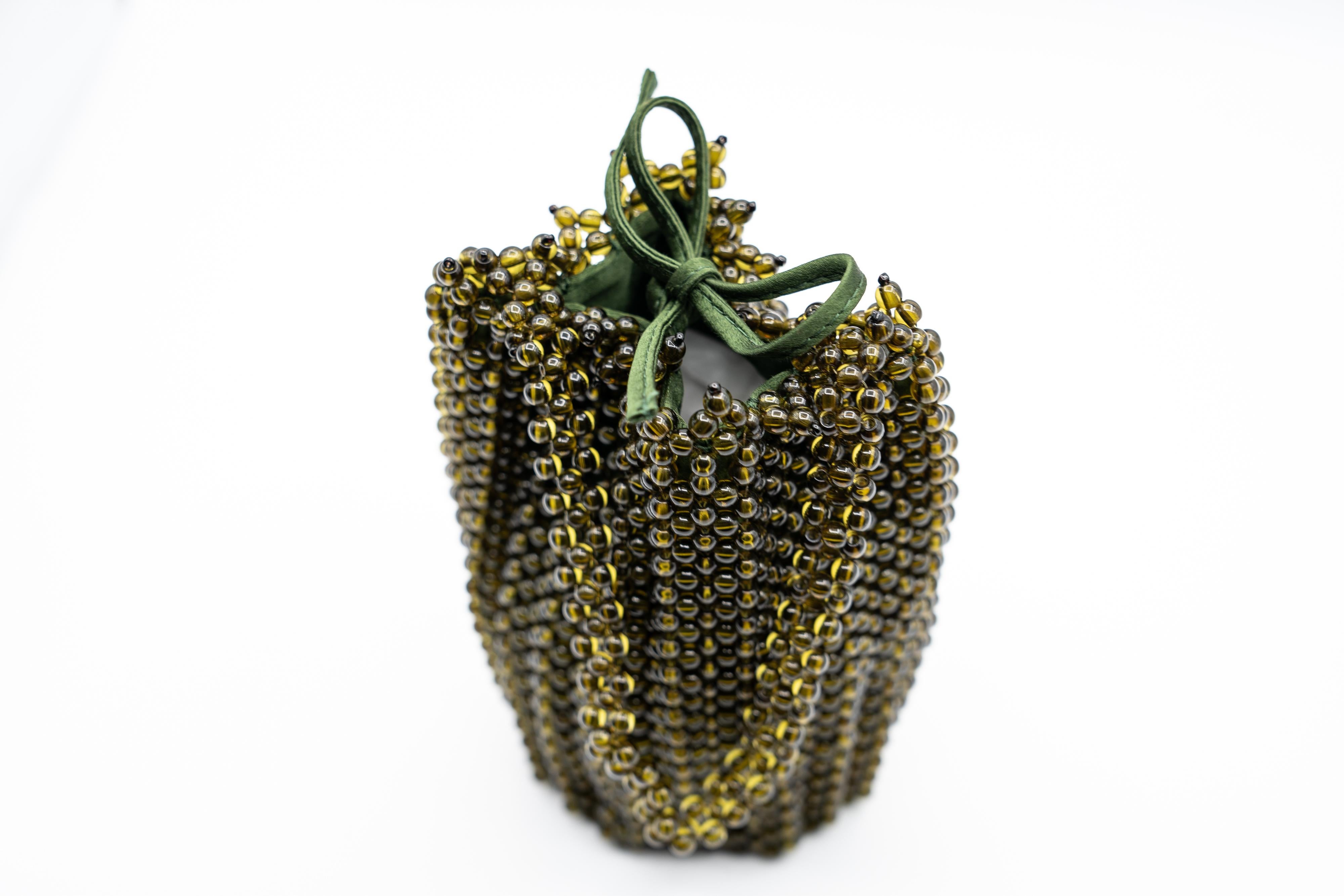 This exquisite vintage Bottega Veneta handbag is a rare collector’s piece. The intricate beaded exterior is crafted of translucent green lucite beads, creating a mesmerizing textured surface that shimmers under the light. The delicate beading