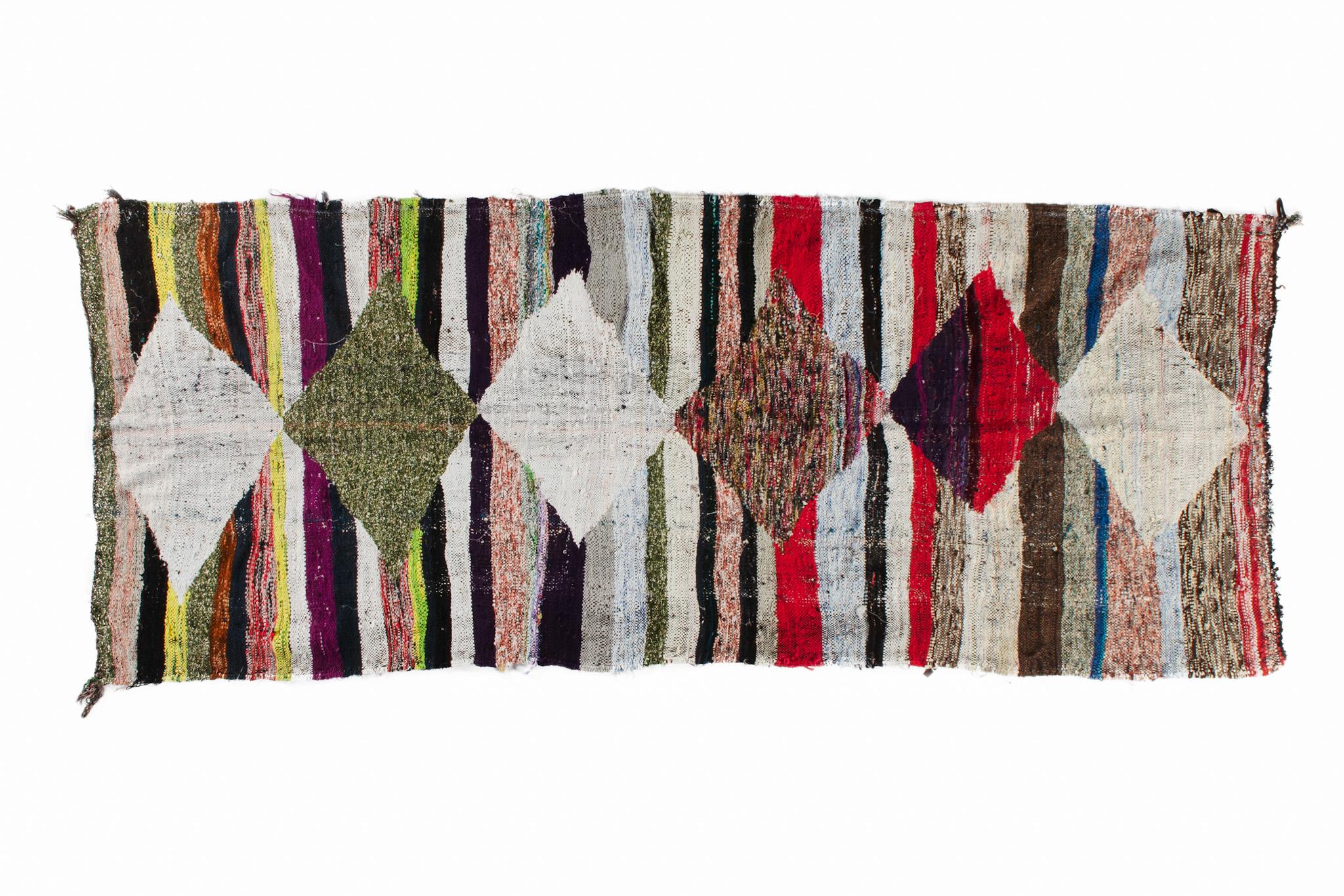 Les tapis boucharouites sont constitués de pièces de vêtements multicolores. C'est le tapis recyclé le plus authentique que vous ayez jamais vu ! Dimensions : 3.4'х8' / 249x104 cm.

La boucharouite est une ancienne technique manuelle qui consiste à