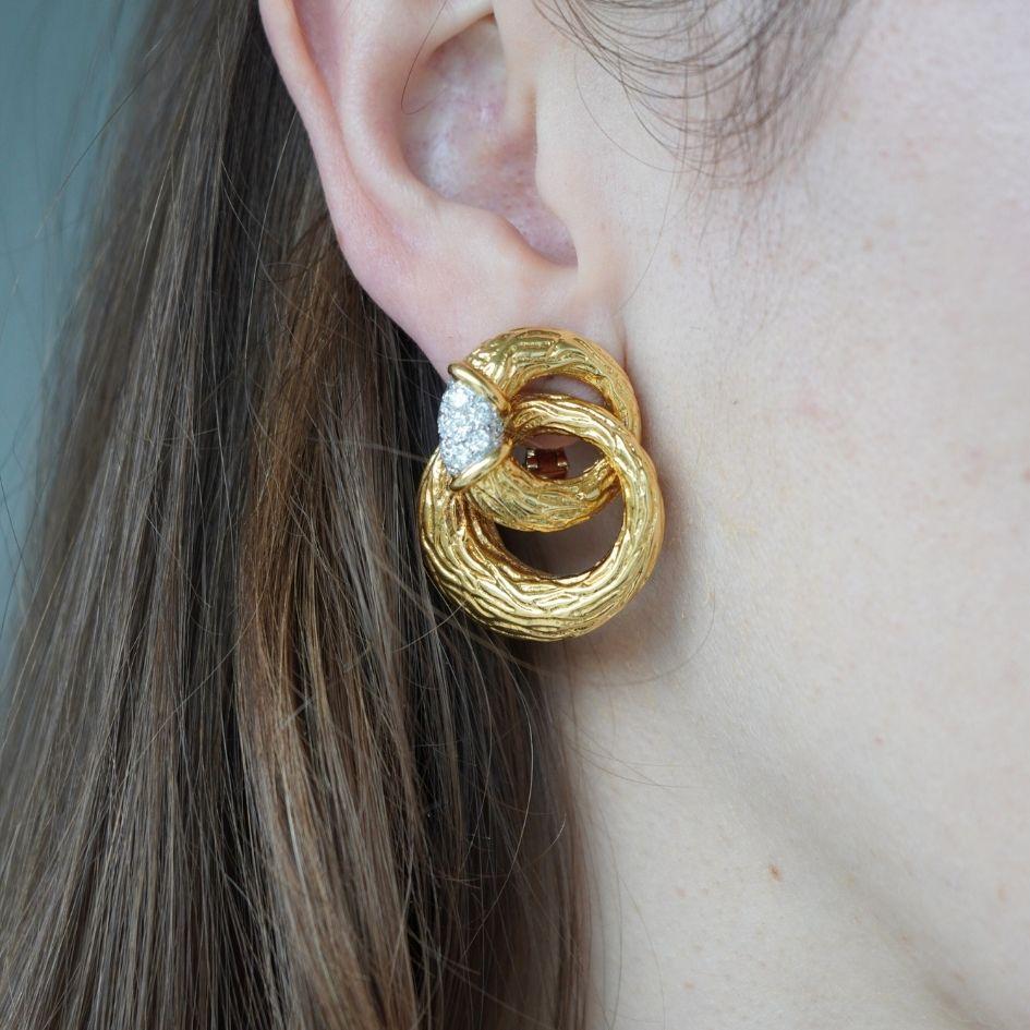 Crafted in France circa 1970s, these Boucheron double circle earrings embody the bold and tactile style of the era. Designed in 18k yellow gold with a deeply textured finish, each earring features two interlocking circular forms accented at the