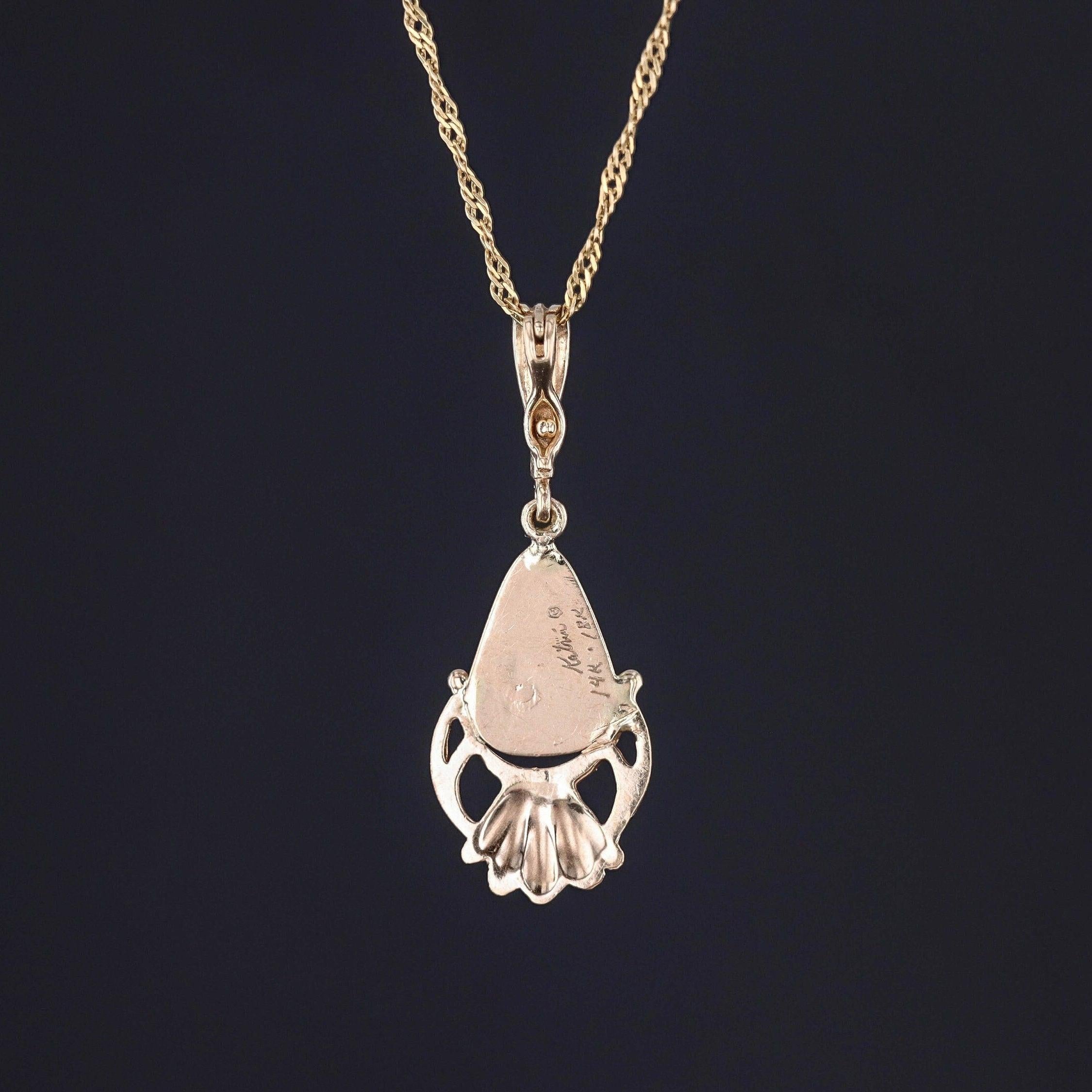 Ce pendentif vintage (circa 1980-1990) présente une opale de roche colorée en or 14k.

Le pendentif mesure 1,6 pouces du haut de la bague au bas par 0,6 pouces de large, et il est en excellent état. Le revers est gravé à la main avec le nom du