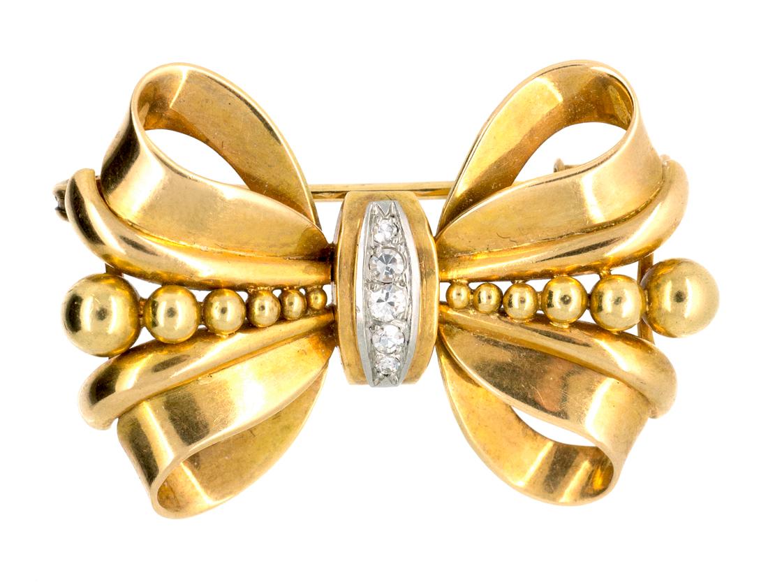 An 18 karat yellow gold tied bow brooch with brilliant cut diamonds set to the centre. French marks.
Measures 40mm in length x 25mm high.
Vintage piece in the Victorian style.
20th century, French circa 1950.

Stock no. 0440