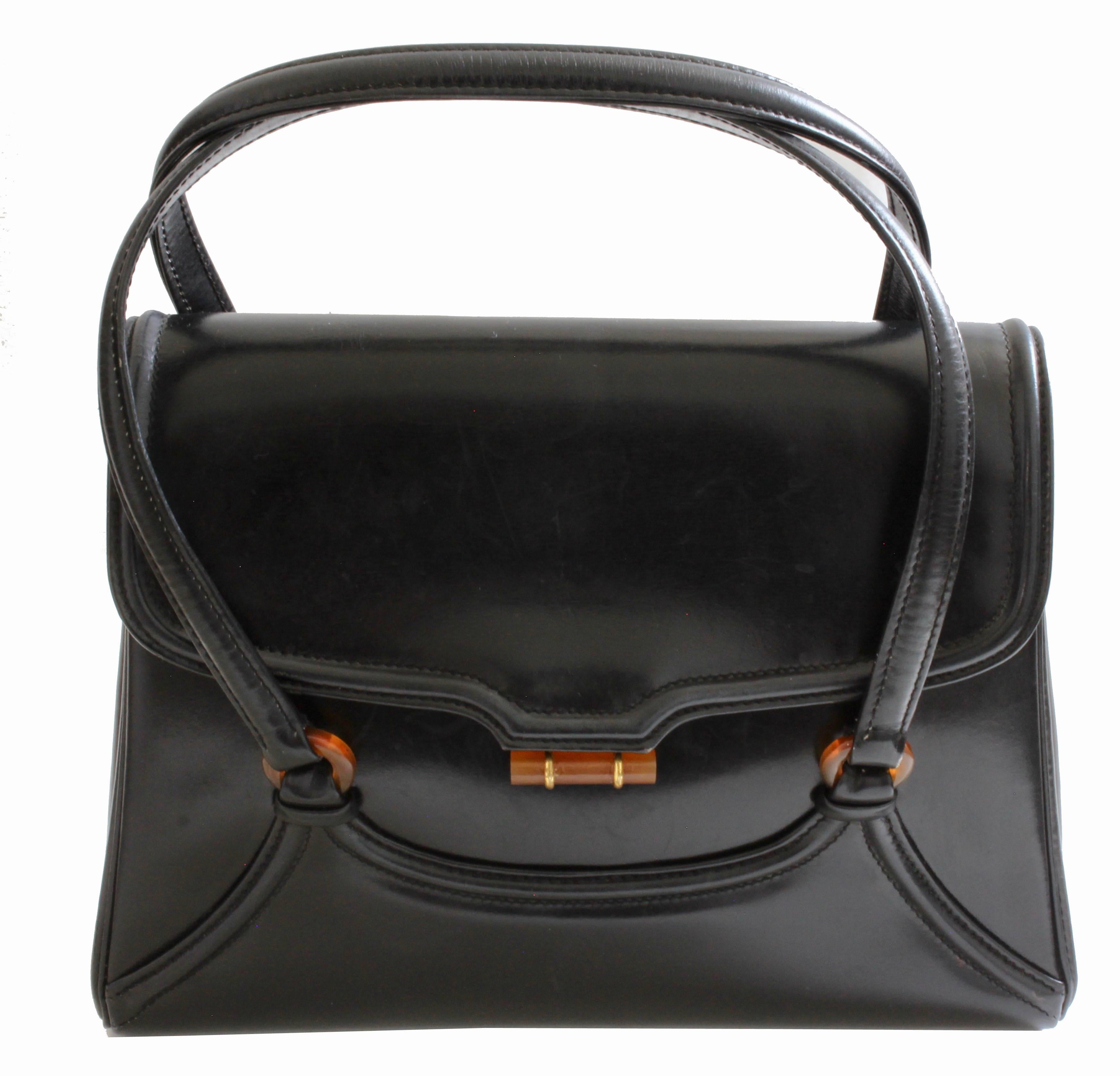 This vintage bag was made in Italy for BONWIT TELLER, most likely in the 1960s.  Made from black box calfskin leather, this bag is quality made: it features two top handles and Bakelite hardware! It opens by pushing the bakelite barrel up and inside