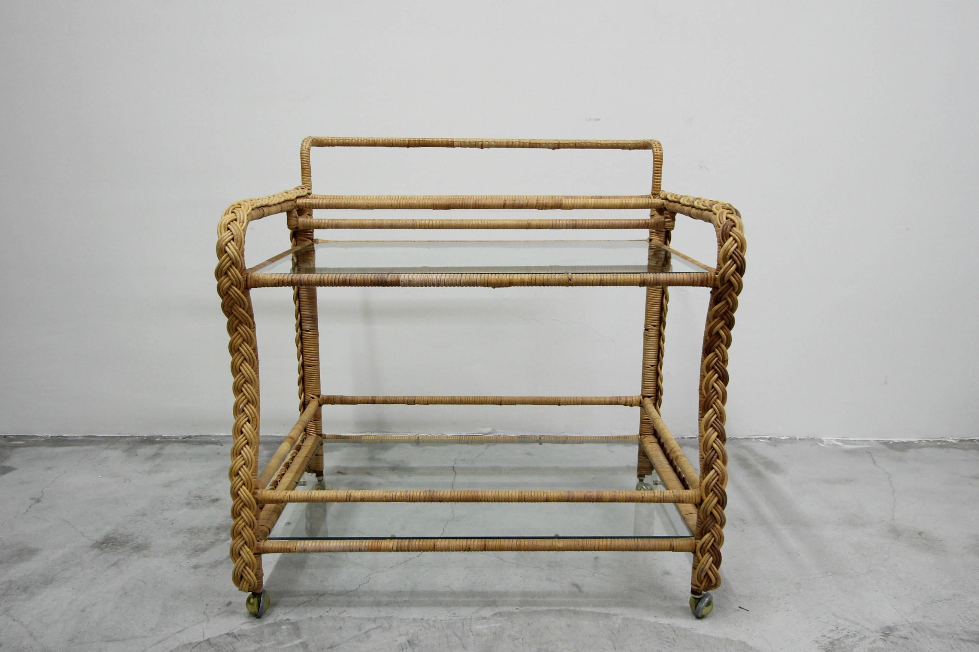 Simple, clean, two-tier, braided wicker bar cart. Features two glass shelves. Brass casters for easy movement.

Perfect in small spaces, great for a sun room, easy to roll outside by the pool for your summer shindig.

Excellent condition, no