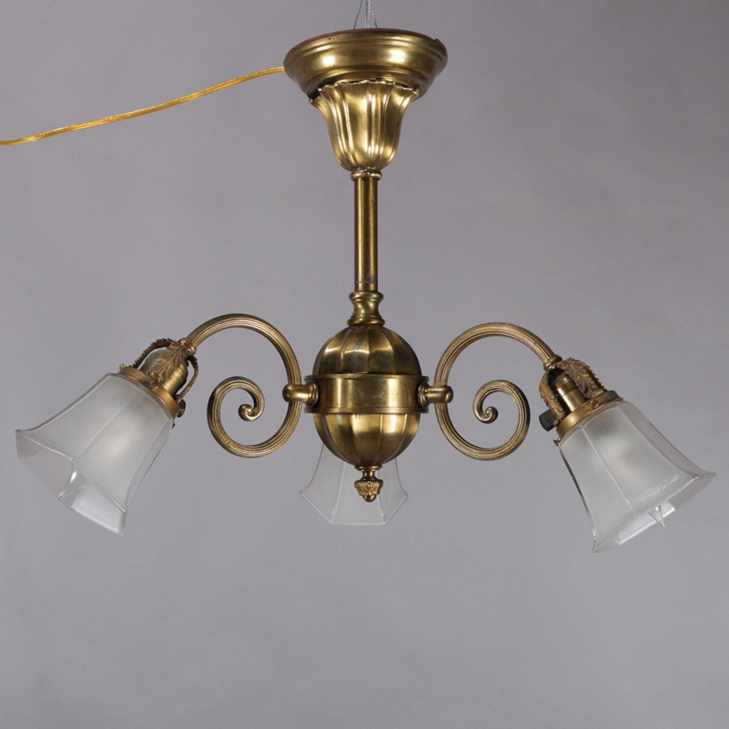 A vintage branch chandelier features brass frame with column terminating in faceted pendant and having three scroll arms with lights having frosted glass shades, circa 1920

Measures: 19.5