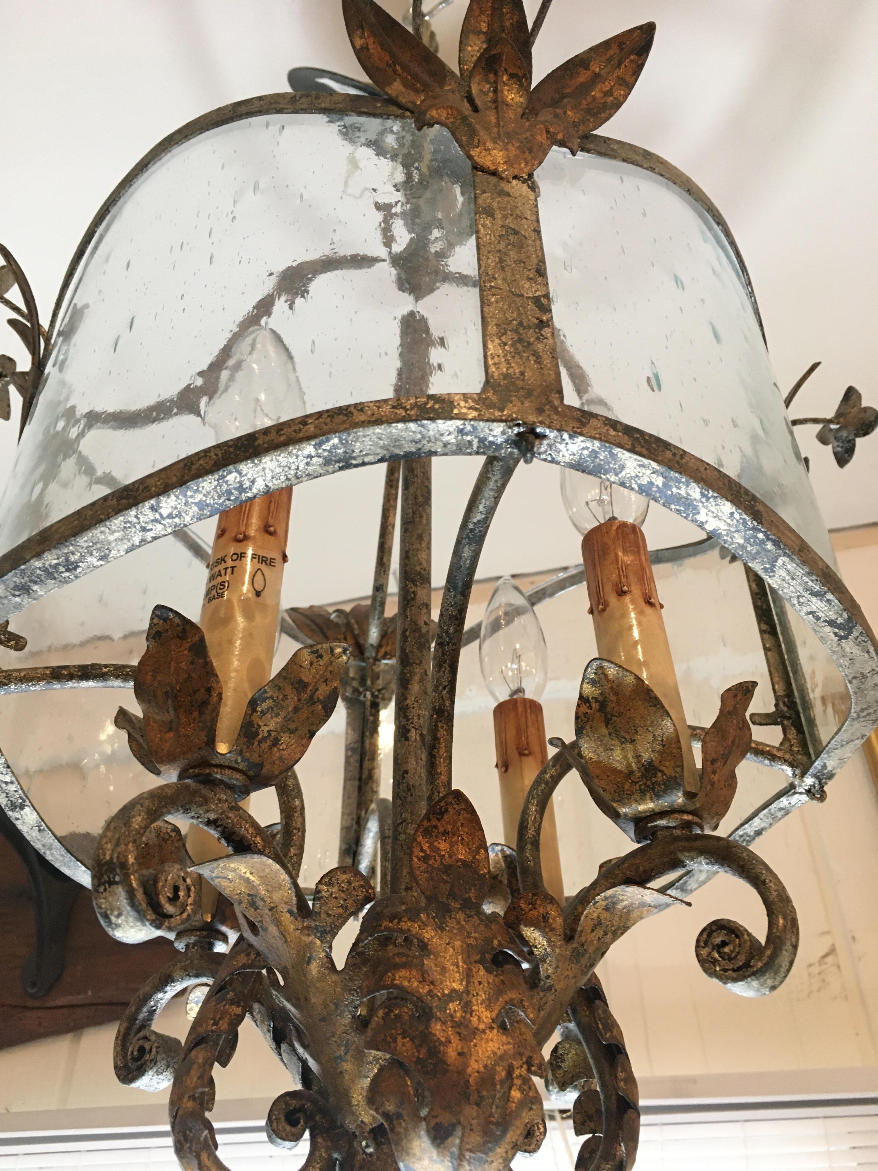 An elegant medium sized vintage light fixture having leafy brass arms and decorative base and particularly beautiful aged curved glass.