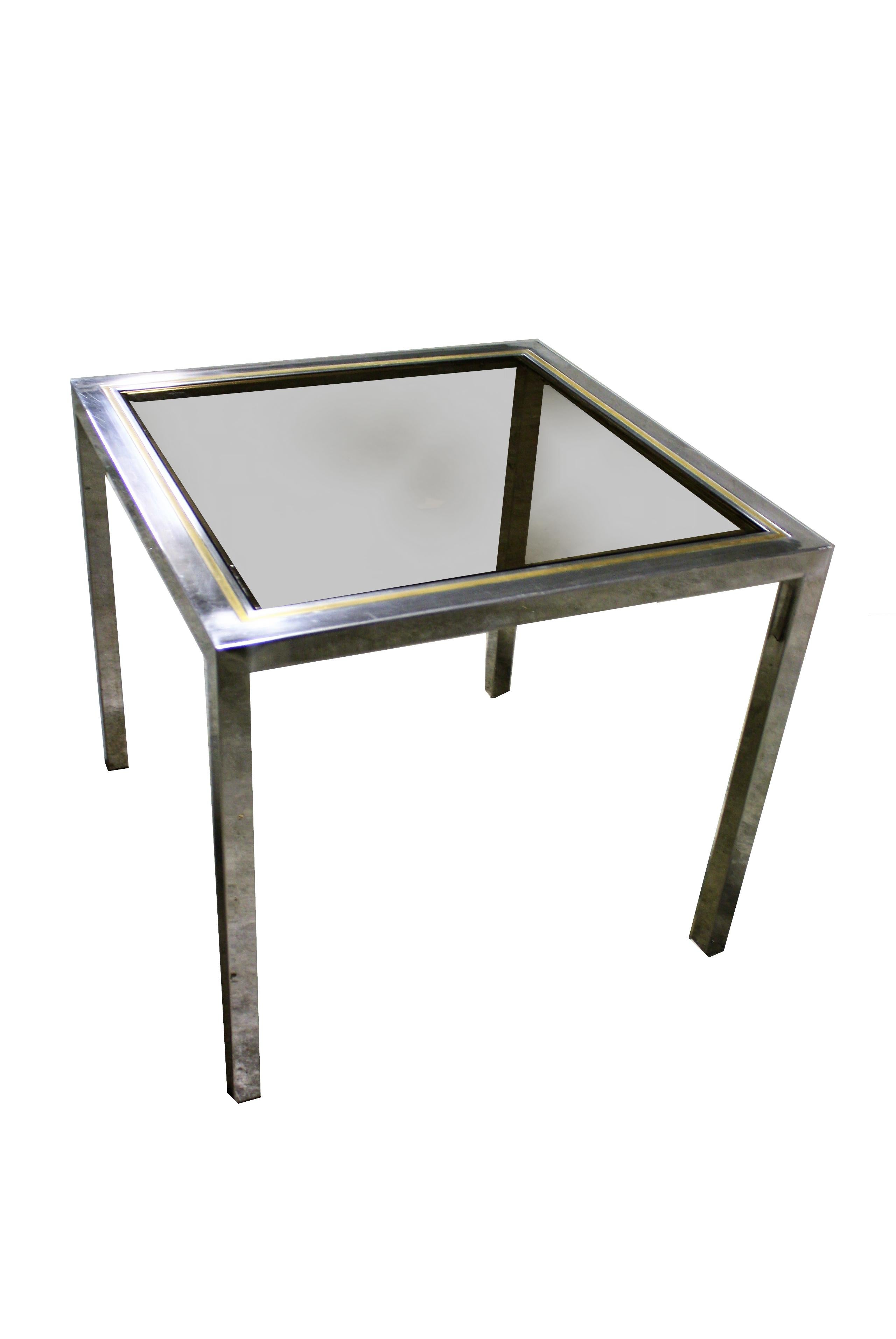 Vintage brass and chrome table in the style of Willy Rizzo.

The table can be used as a side table or as a small dining table (ideal for four persons).

It features a two-tone chrome and brass frame with smoked glass.

The table is in good