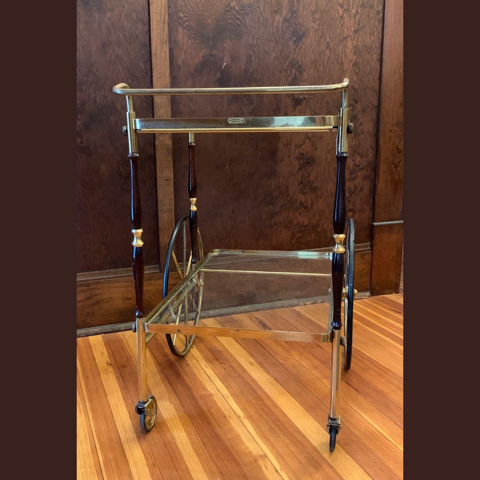 To add a beautiful French flair to a bar area, try this elegant vintage two-tier rolling bar cart, crafted circa 1950. Built in brass and rectangular in shape, the dessert table stands on two small and two large round wheels with rubber tires that