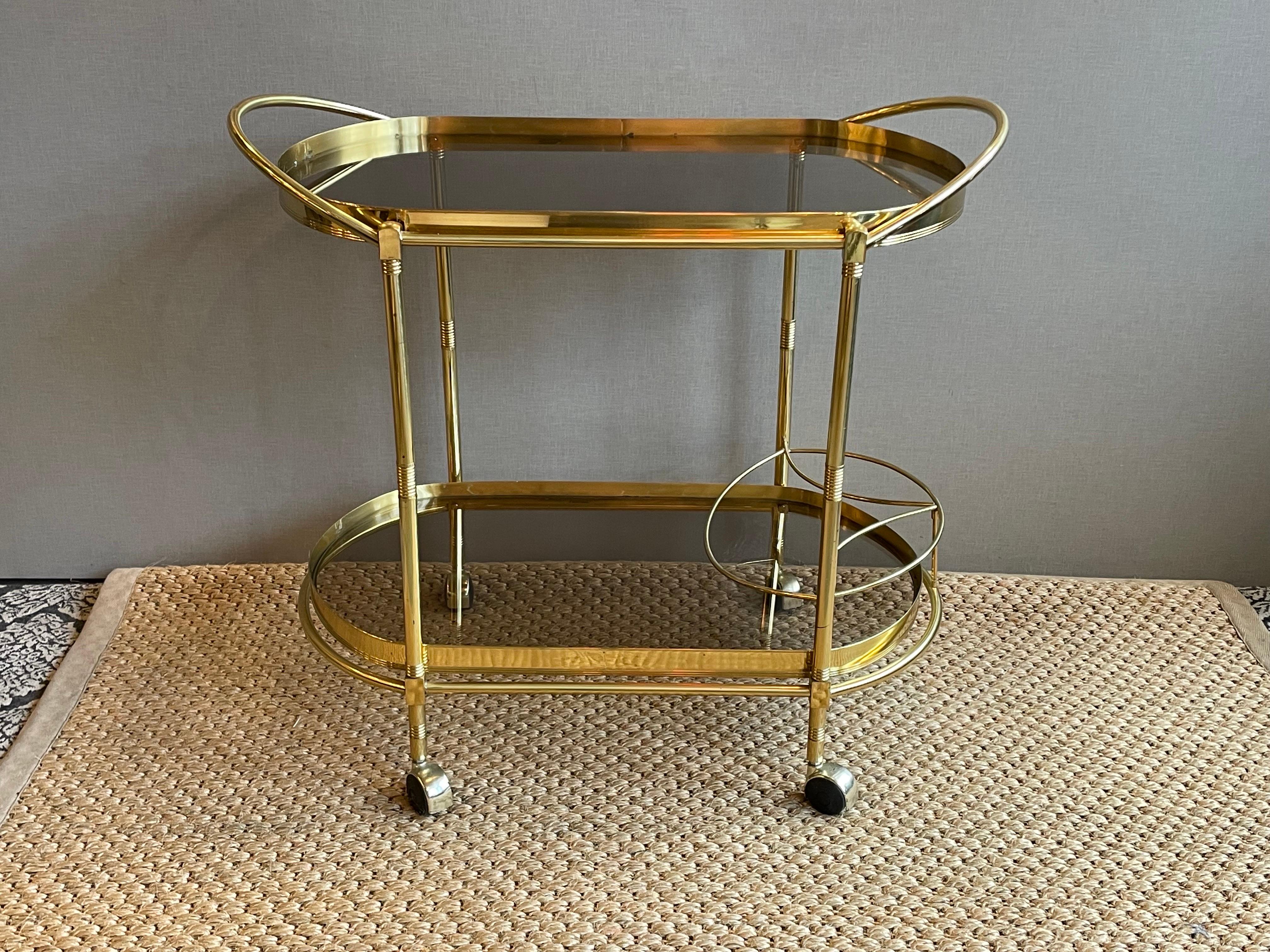 This is a wonderful sturdy vintage Brass and glass bar cart with two tiers and area to hold bottles 
It’s in wonderful vintage condition 