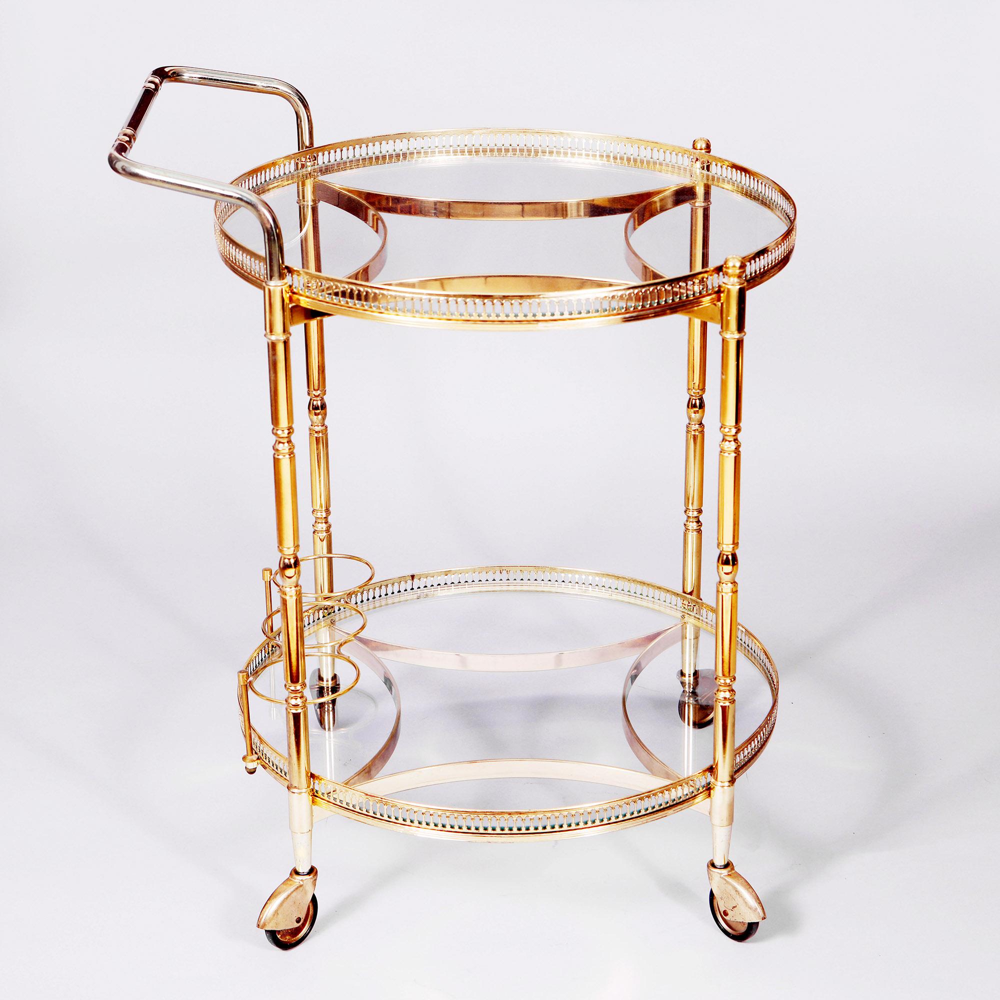 A vintage circular drinks trolley with two glass tiers within polished brass galleries, the lower one with a bottle holder, the whole raised on four small castors. 
France, circa 1970

Overall Height 74 cm
Height of top tray 65 cm
Width 53 cm