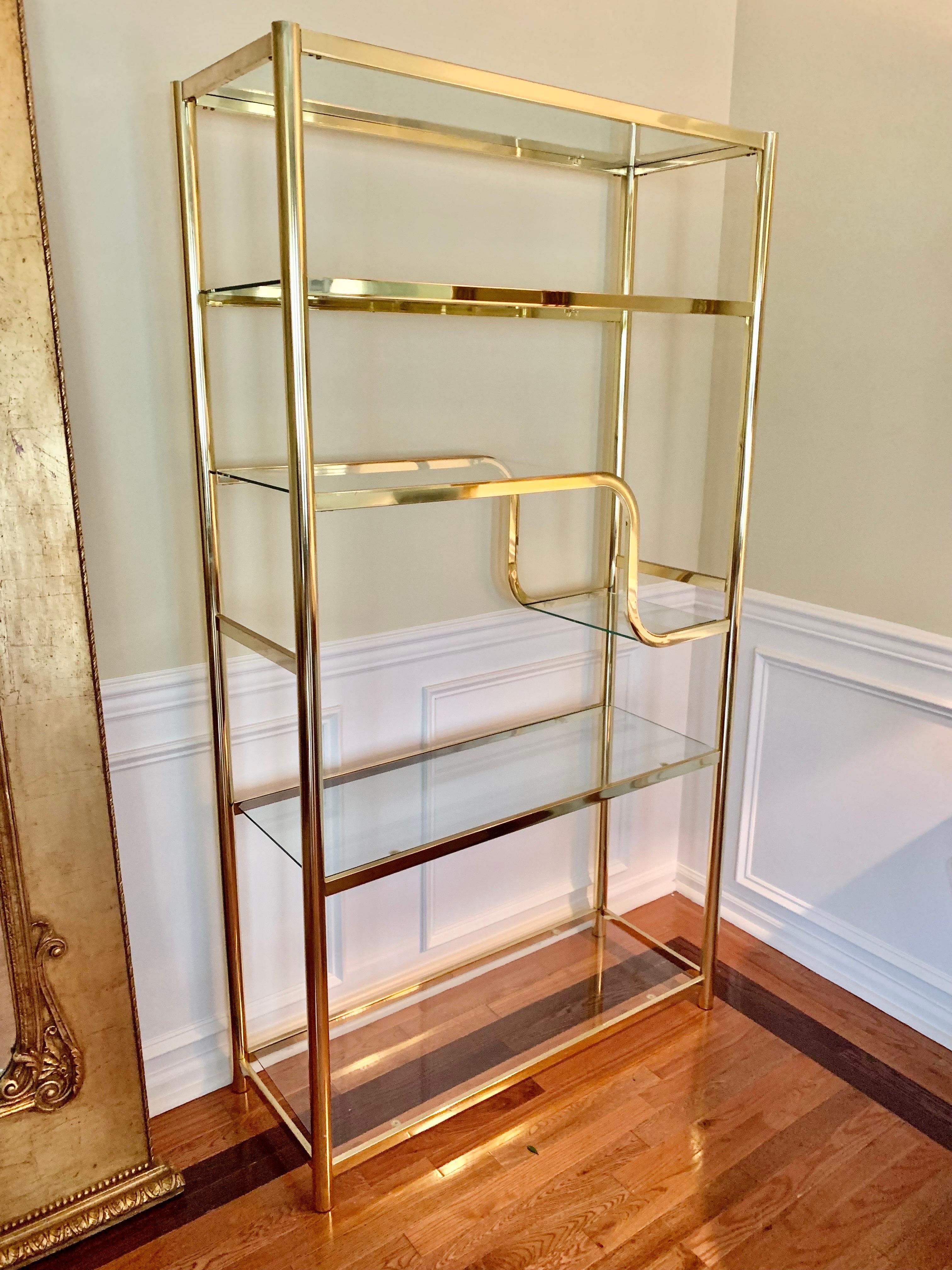 Elegant brass etagere by Design Institute of America in the style of Milo Baughman. Includes four full length glass shelves and two smaller ones.