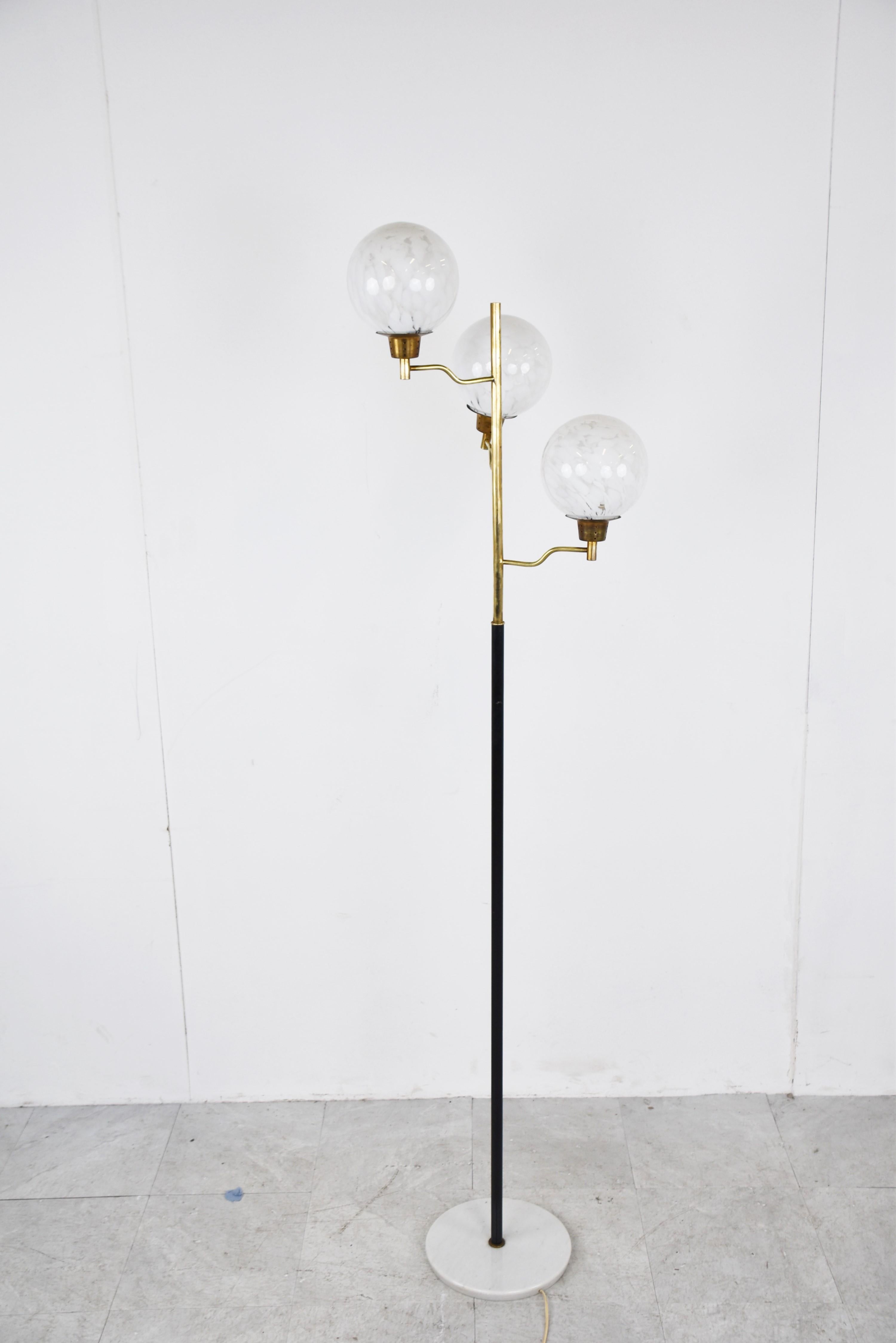 Mid-Century Modern brass and balck metal floor lamp with three murano glass globes. 

Beautiful round marble base.

This lamp emits a warm light, creates a lovely atmosphere and has a timeless design.

Good condition

The lamp works with