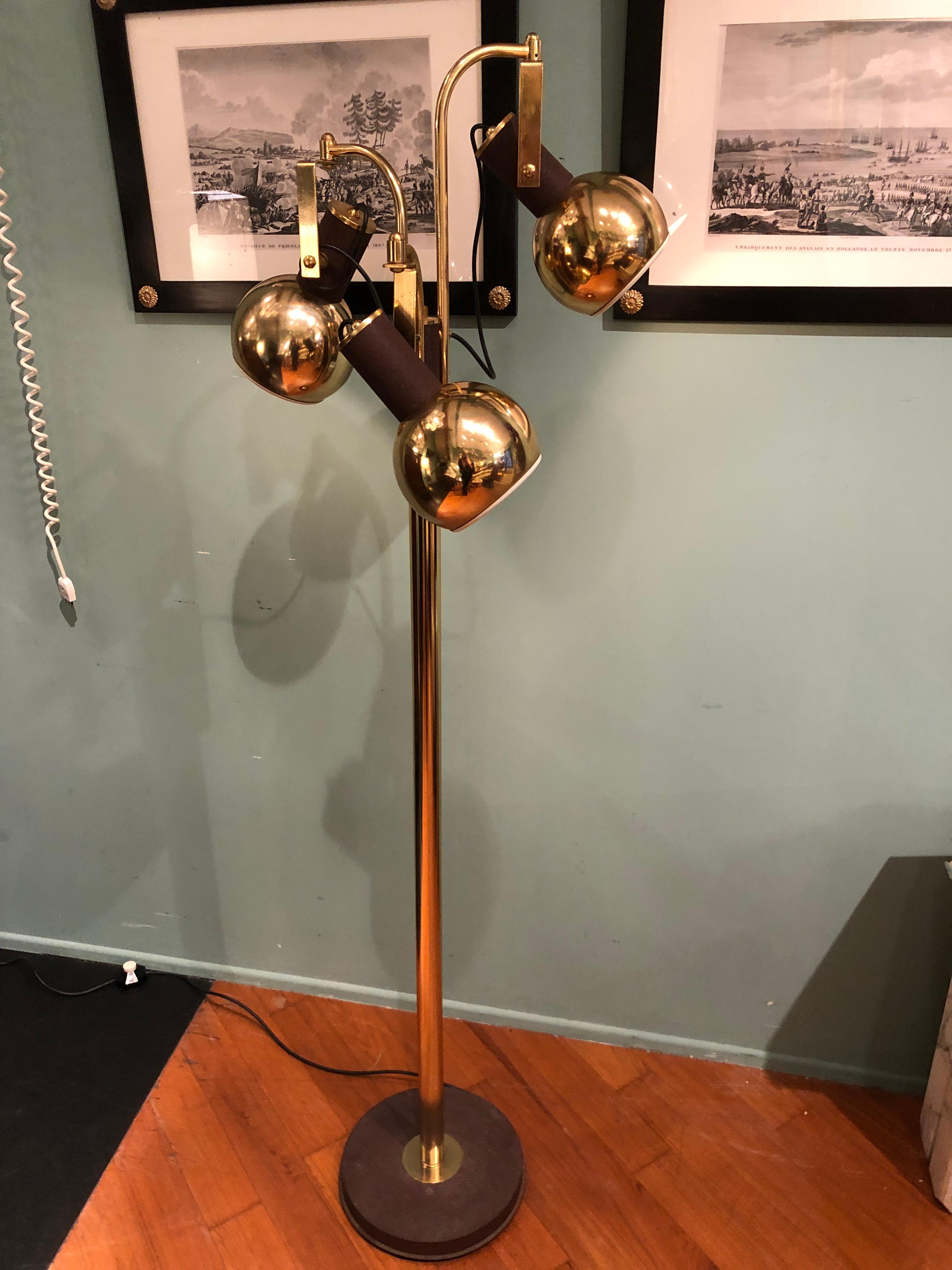 Reading floor lamp with three spherical shaped lights that can be adjusted to point light up or down. The structure is made of brass and the rounded base is made of iron with rusty color. This lamp shows very good conditions with wears coherent with