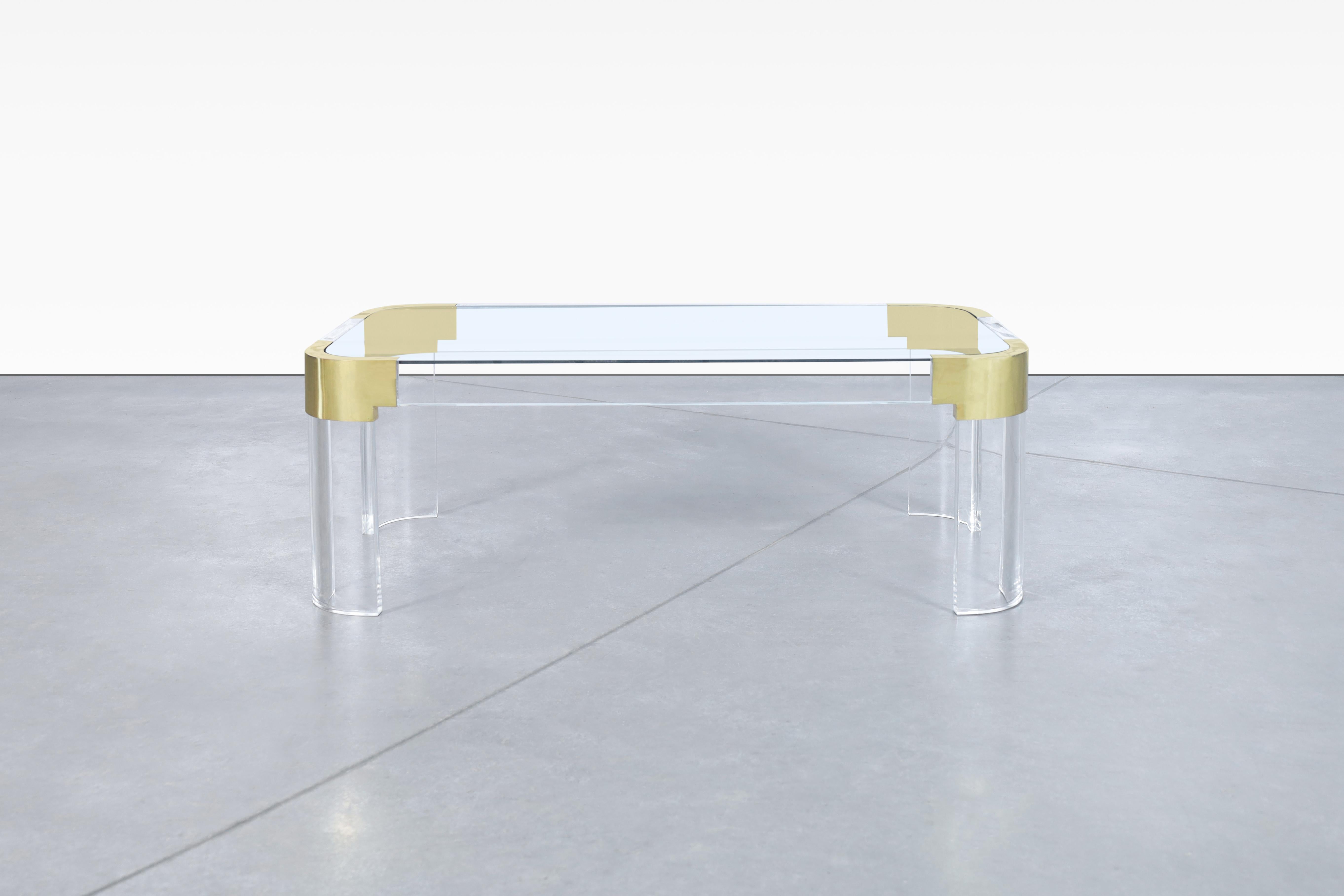 Beautiful vintage brass and lucite coffee table designed by Charles Hollis Jones and manufactured in the United States, circa 1970s. Introducing a coffee table like no other - one that showcase elegance and refinement. This coffee table is a part of