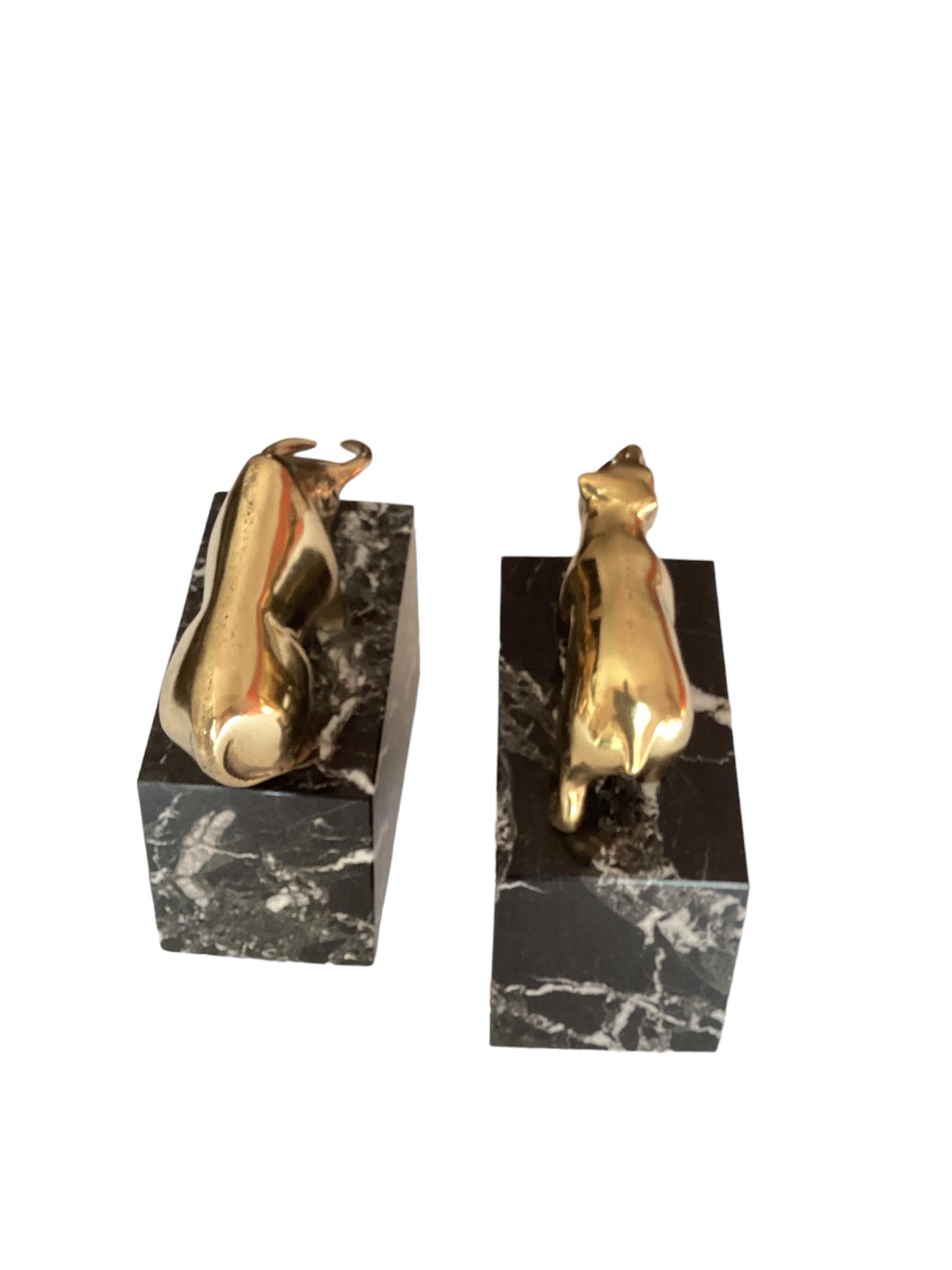 Vintage Mid Century brass bull and bear bookends, paperweights or bookends. These polished Heavy cast brass bull and bear bookends animals are mounted on black veined marble base. Fabulous Mid-Century Modern meets Art Deco style, sure to add some
