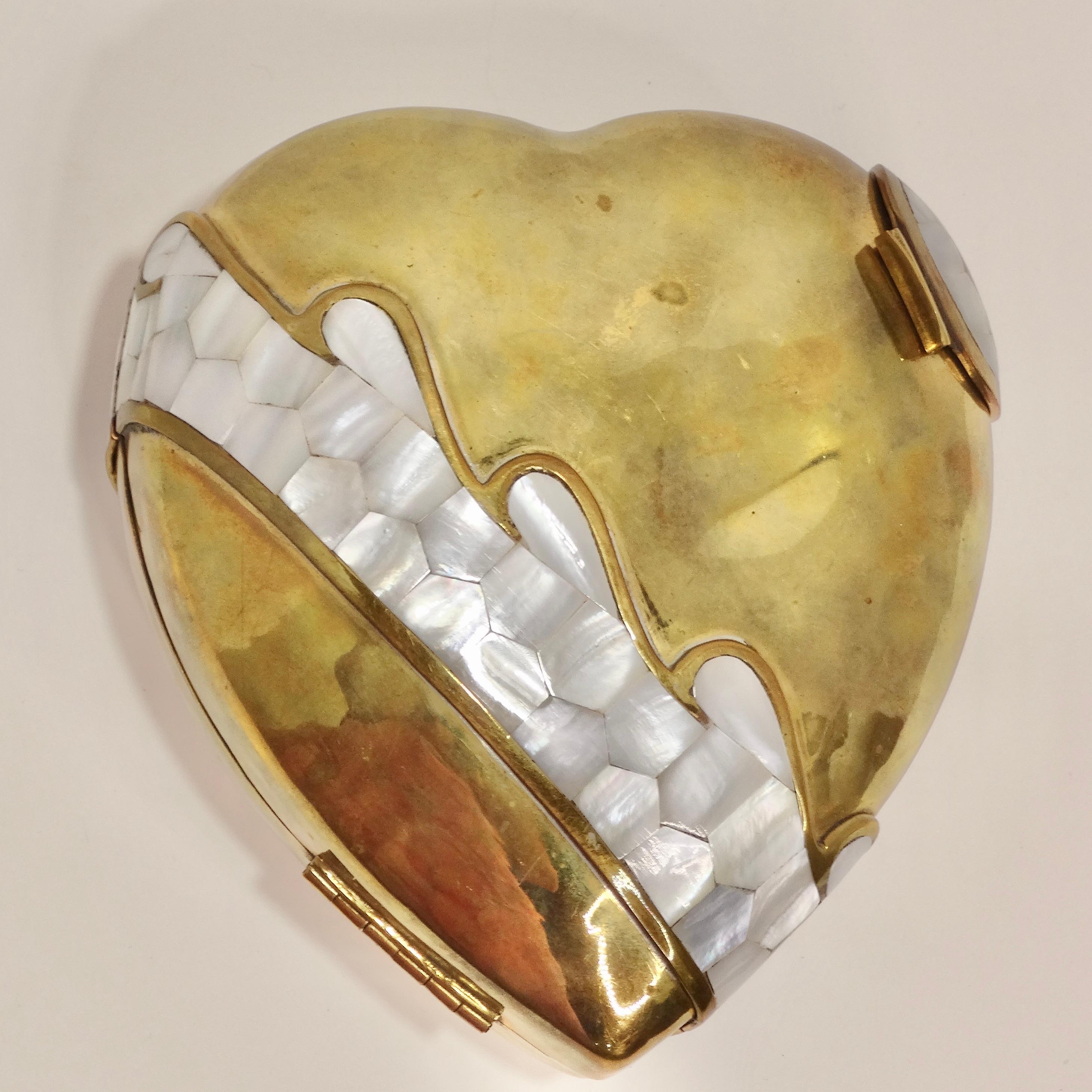 Fall in love with this vintage Brass Heart Shaped Clutch, a true gem that captures hearts with its enchanting design. Crafted with exquisite attention to detail, this clutch features a delicate mother of pearl enamel, adding a touch of