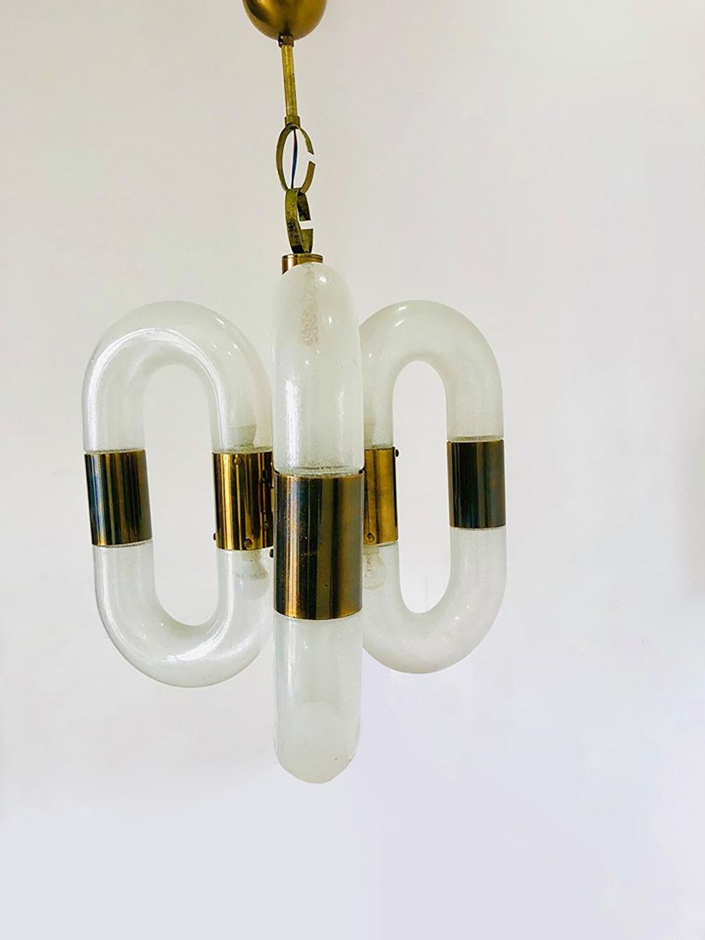 This brass and Murano glass chandelier is an original decorative object designed by the Italian glassworker Aldo Nason and realized by the prestigious glass factory Mazzega in Venice in the 1970s.

This elegant chandelier is made of brass and
