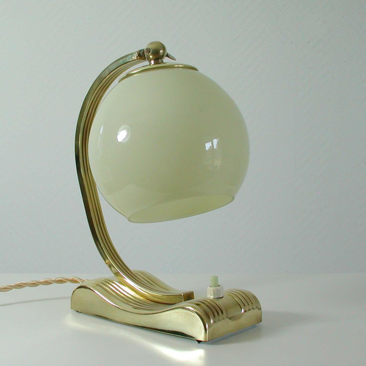 This vintage table or bedside lamp was made in Germany in the 1930s during the Art Deco period. It is made of polished brass and has got an adjustable opal glass lamp shade. Rewired with new silk wiring for use in US, Europe. Brass polished and very