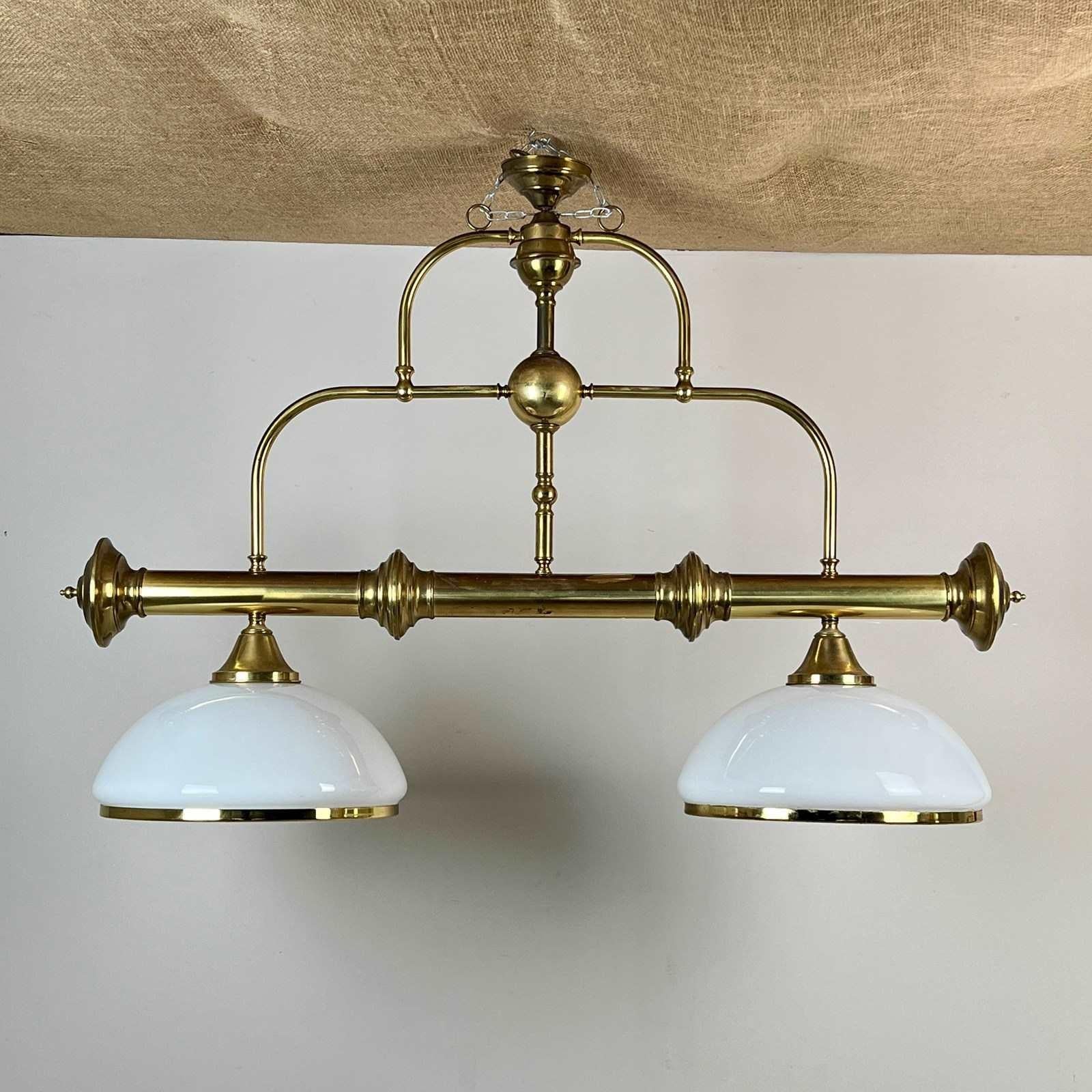 Plafón de latón y opalina de estilo vintage. El marco es de latón tubular con decoración de bola, husillo y remate. Dos grandes tulipas de cristal con adornos de latón. Ideal para iluminar una isla de cocina, un pasillo, un lavadero, un bar o una