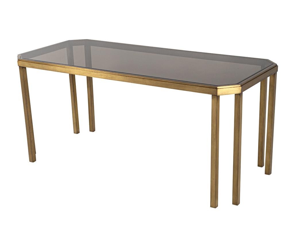 Introducing the stunning Vintage Brass and Smoked Glass Console Table, a truly unique piece that seamlessly blends sleek modern design with vintage charm. Crafted in Italy during the 1970’s, this console table exudes elegance and sophistication. The