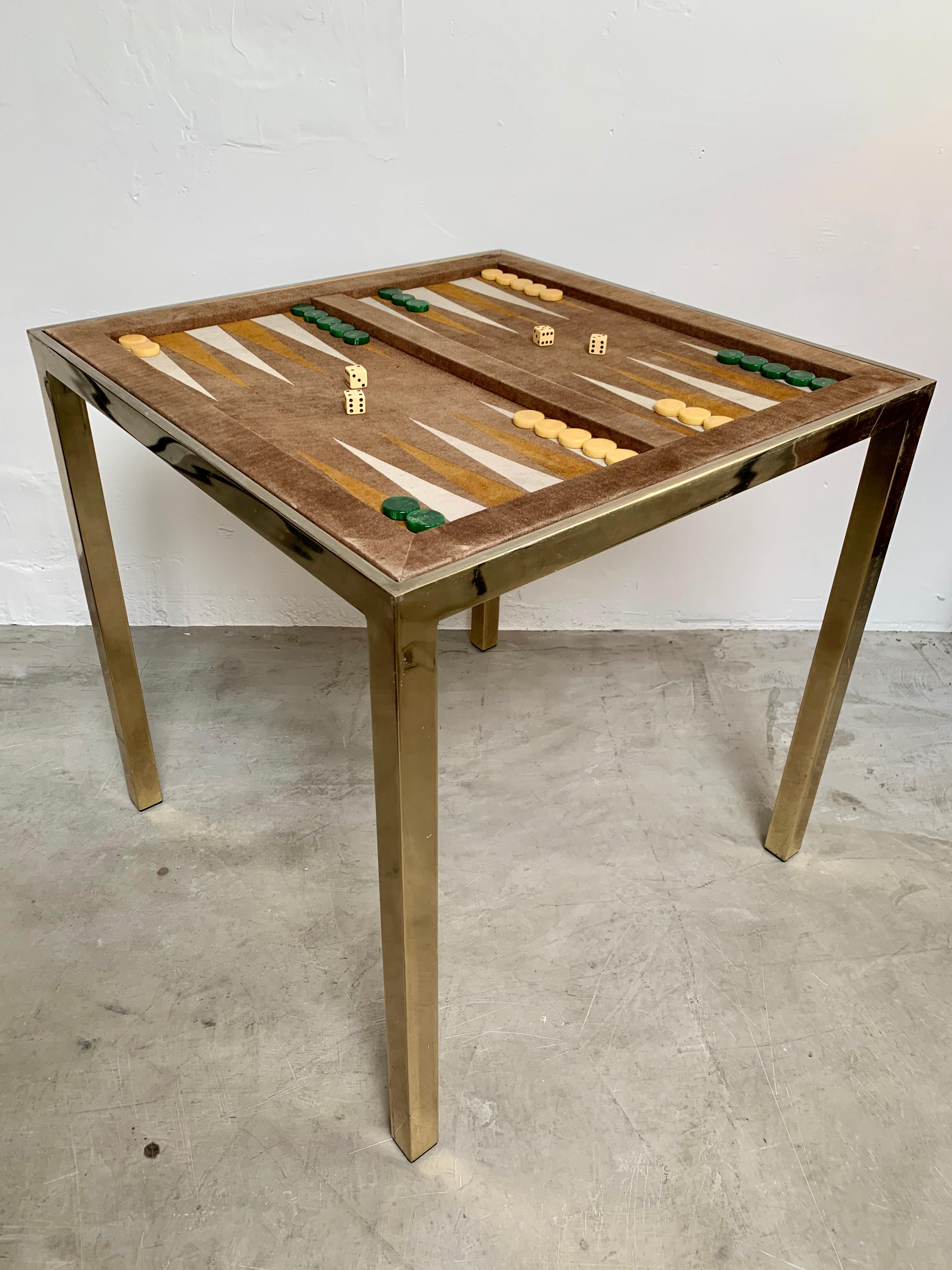 Perfectly sized vintage backgammon table by Milo Baughman. Chrome frame (with brass patina), with inset brown suede backgammon board. Board flips over to suede chess board. Vintage bakelite game pieces included along with bone dice. Glass tabletop