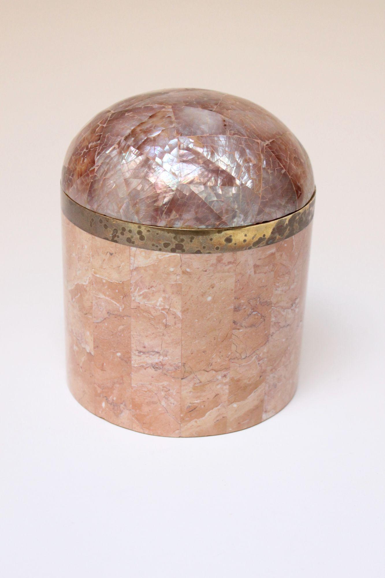 Boîte à bibelots vintage de style Maitland Smith ou Robert Marcius (vers les années 1980, États-Unis).
La boîte/jarre est composée d'une pierre corallienne rose tessellée, d'une quincaillerie en laiton et d'un couvercle bombé en coquille d'ormeau