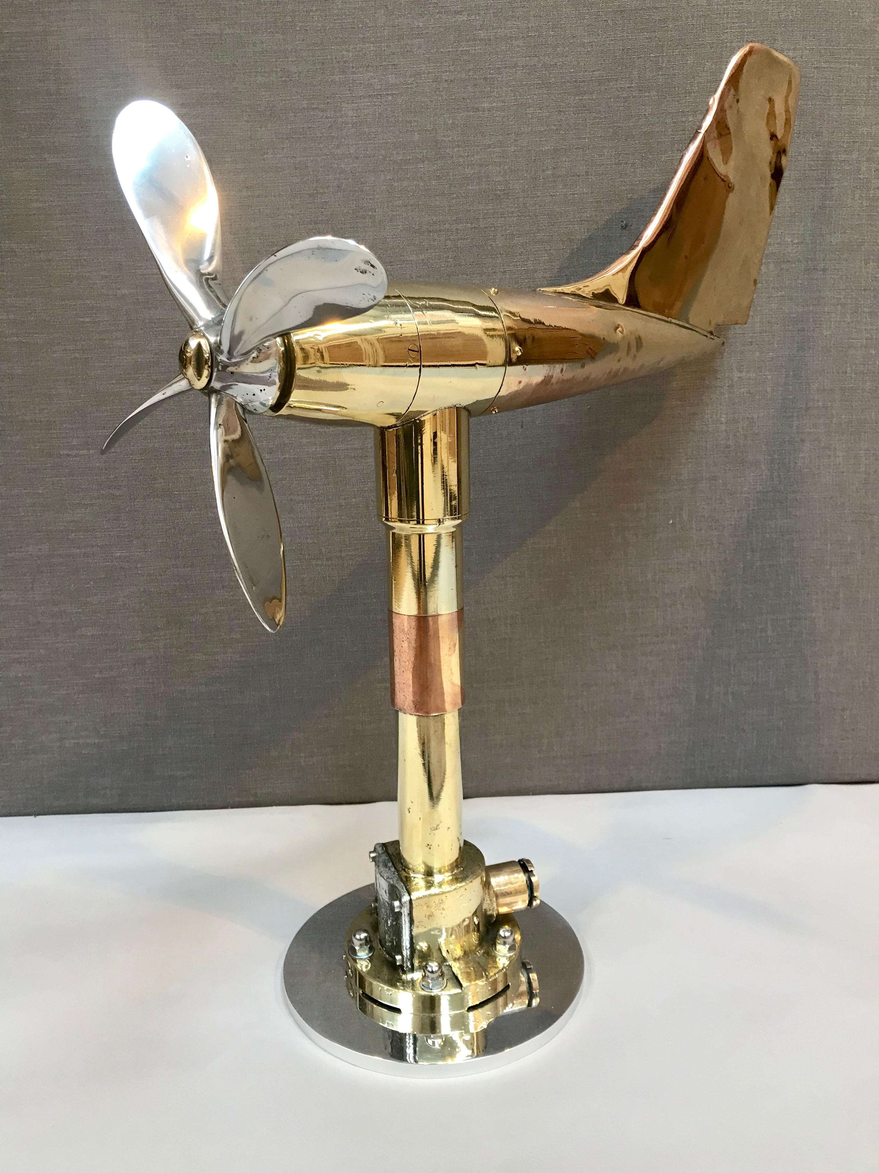 A vintage brass anemometer / wind direction indicator, fashioned as an aircraft fuselage with a tail plane stabiliser and propeller, rotating on a tapered, tubular pillar and a circular base.



 