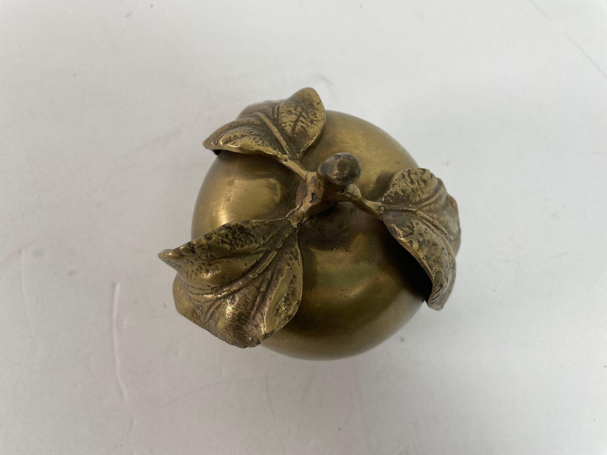 Vintage brass apple sculpture paperweight in very good condition with a light patina all around.
Polished brass apple with 3 leaves with fine details, heavy weight to use as a paperweight or just a decorative vintage Art object on a desk or