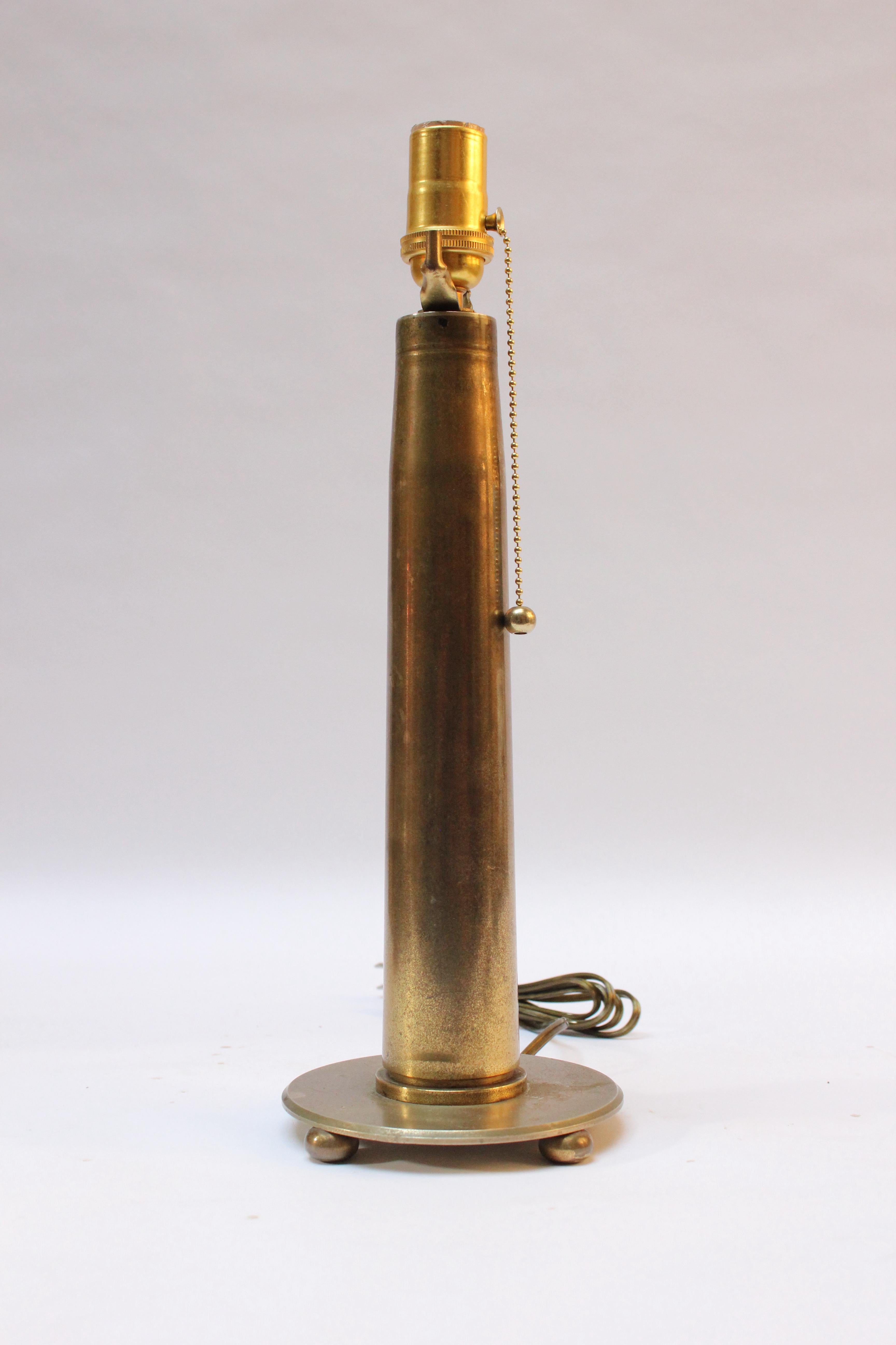 Circa 1930s Trench Art Lamp fashioned from a brass artillery shell mounted to a brass base supported by three ball feet. 
Rich patina present, as shown.
Measures: Height of shell discounting socket: 13.25
