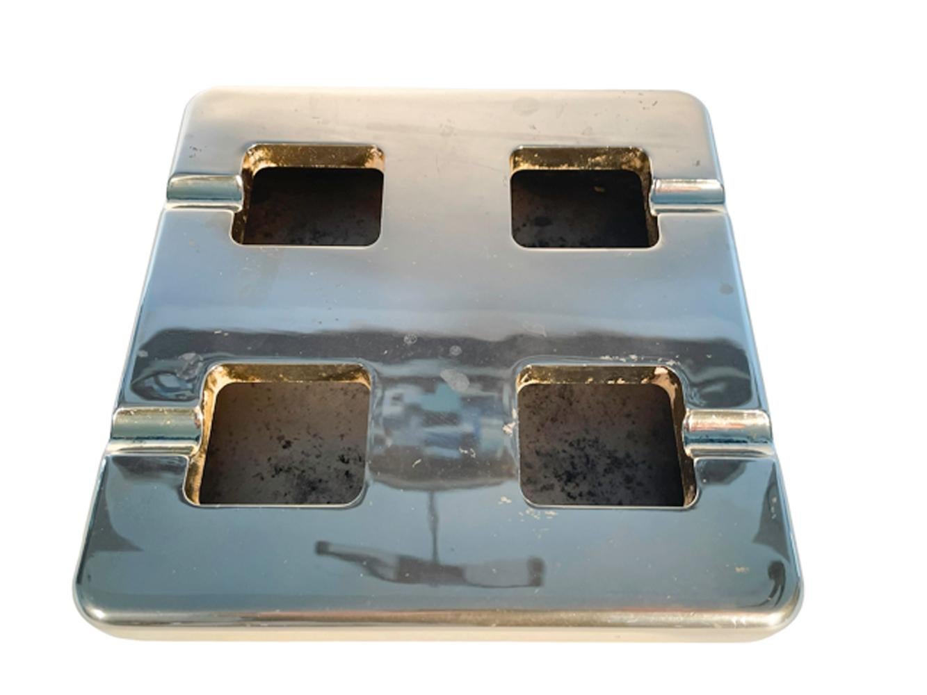 Two-part brass ashtray of box for, the shallow square base with a conforming top fitting over the rim and with four square holes, each with one cigarette rest facing to two of the four sides and creating a clean, minimalist design.