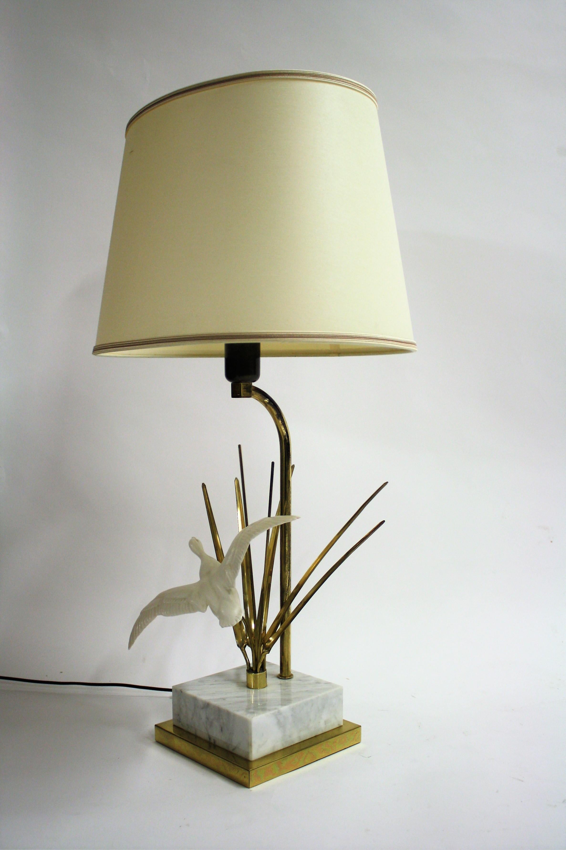 Vintage Hollywood Regency bird table lamp.

The lamp is made of brass, has a marble base and a resin bird sculpture.

Beautiful Hollywood Regency style lamp.

Comes with the original fabric shade with golden lining.

1970s -