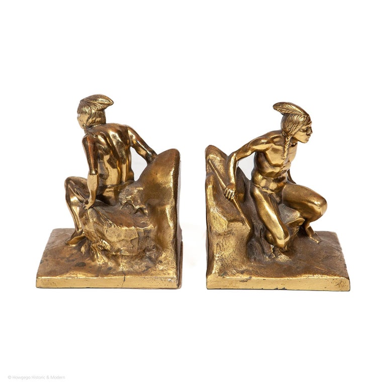 A Pair of Native American Indian Scout bookends in cast brass by Philadelphia Manufacturing Company. The scouts are resting on a rock, a bow in one hand and an arrow in the other. The feather in their hair is a powerful symbol that signifies honor