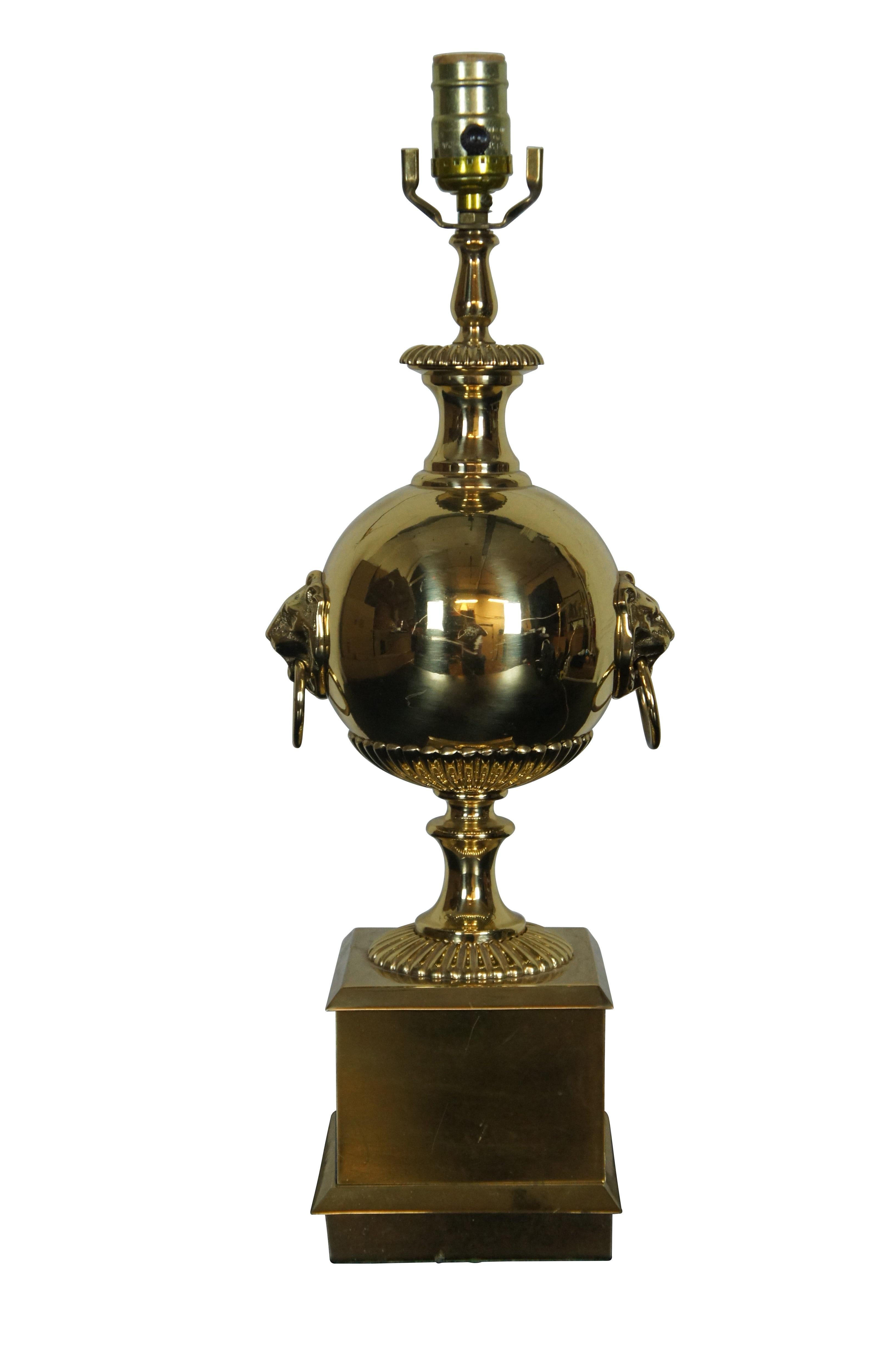 Vintage brass cannonball trophy lamp featuring round urn shaped body with lion head ring knockers and square pedestal base.

DIMENSIONS:
6” x 6” x 20.25” (Width x Depth x Height)