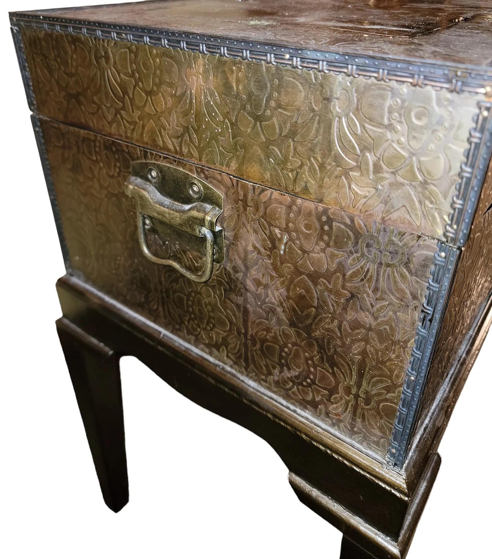 Aggiungi un tocco regale di fascino vintage al tuo spazio con questa cassapanca rivestita in ottone vintage, un mix perfetto di funzionalità e fascino decorativo. La cassapanca presenta un motivo floreale in rilievo sulla sua superficie rivestita in