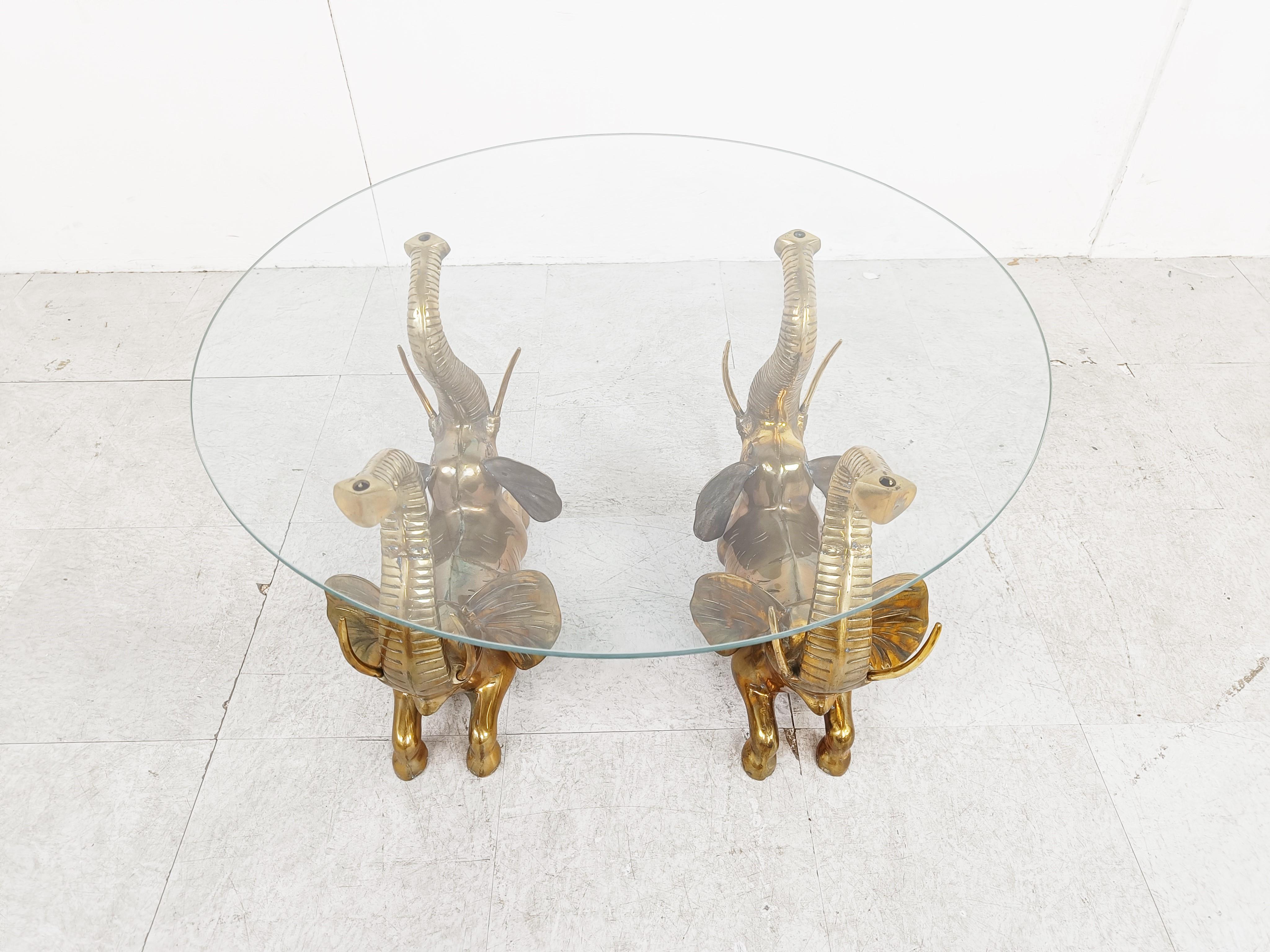 Hollywood regency brass elephant coffee table.

The coffee table consists of a brass base featuring 4 brass elephants and a clear glass top.

We have 4 of these tables available

Dimensions:
Height: 42cm/16.53