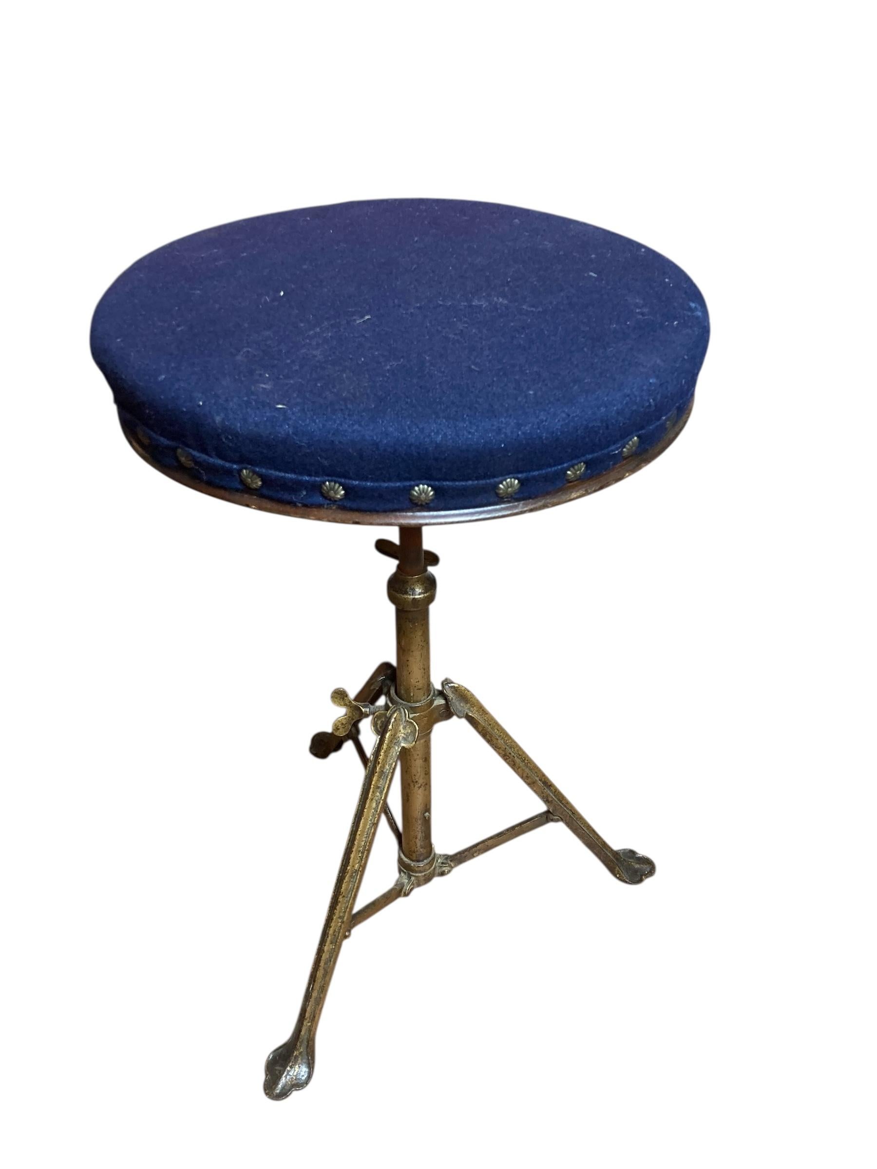 Ausziehbarer Klavier- oder Trommelhocker aus Vintage-Messing, der moderne Eleganz mit industriellem Charme verbindet. Die auffallend blaue Polsterung sorgt für einen kräftigen Farbakzent, während die Messingakzente einen Hauch von Raffinesse