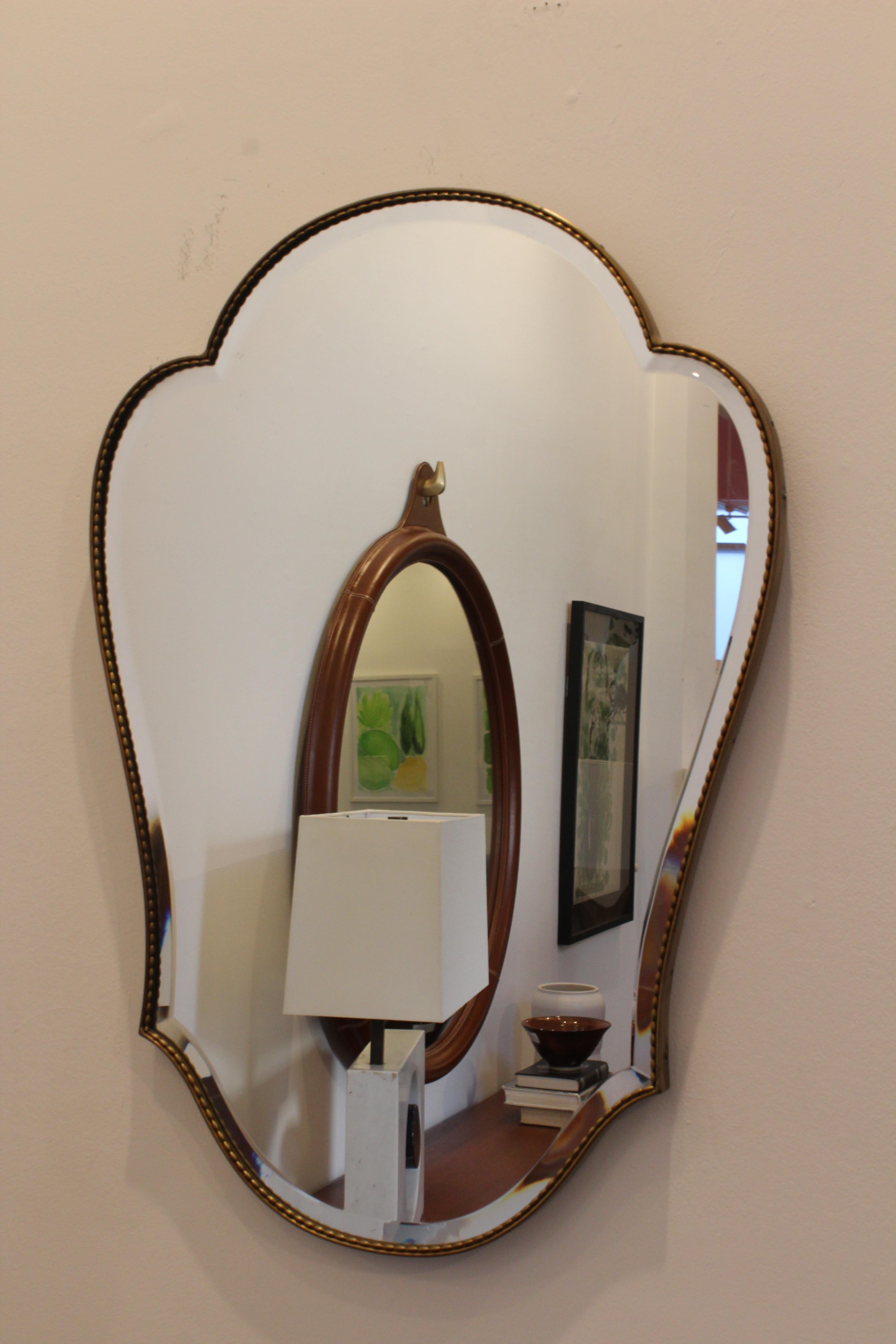 Vintage brass framed mirror with a braided detail along the frame. In good condition with patina.
            