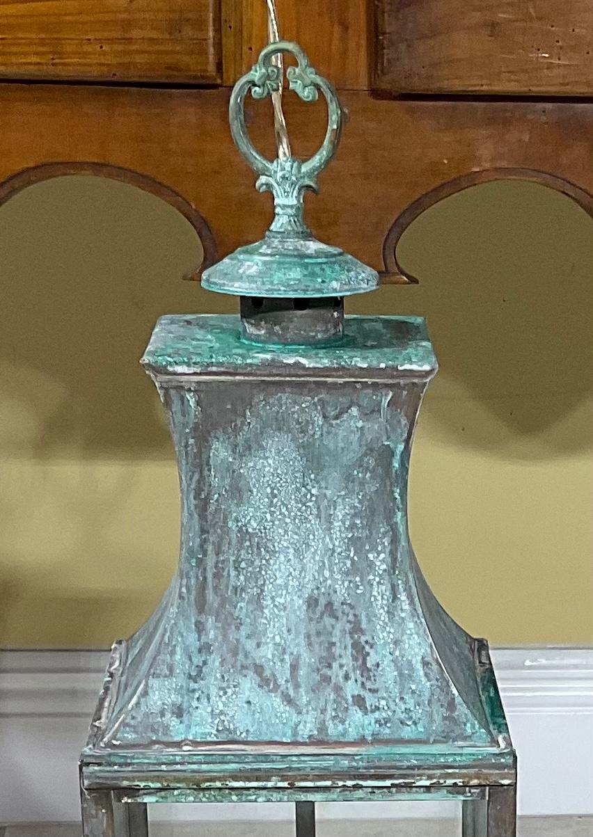 Elegant hanging lantern made of solid brass, with two 60 watt lights, suitable for wet locations ready to use, great oxidized patina and four decorative foots at the bottom of the lantern. 
Newly Rewired and ready to use.
 