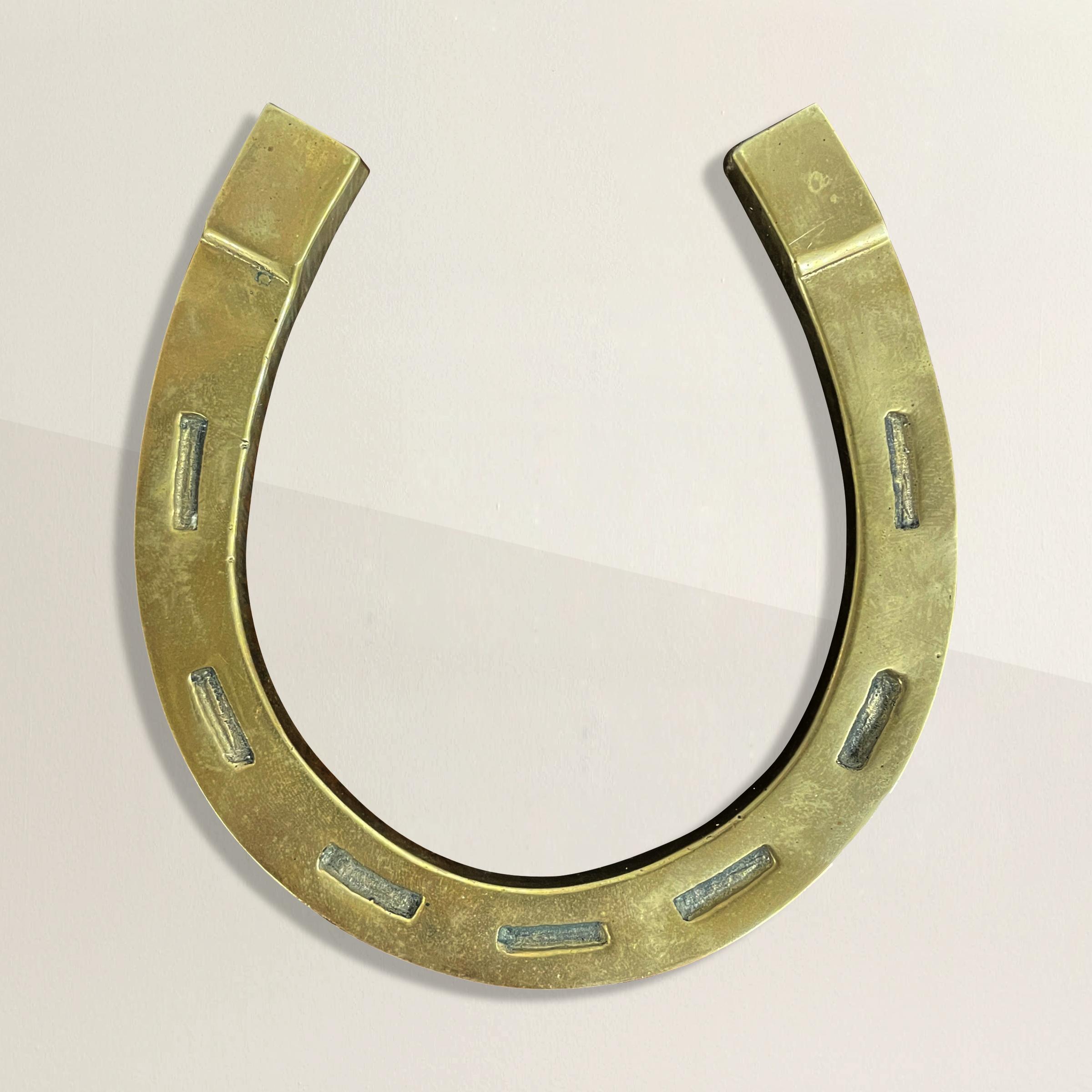A playful vintage brass horseshoe paperweight meant to bestow good luck, prosperity, and good fortune--or just hold the papers in place on your desk.