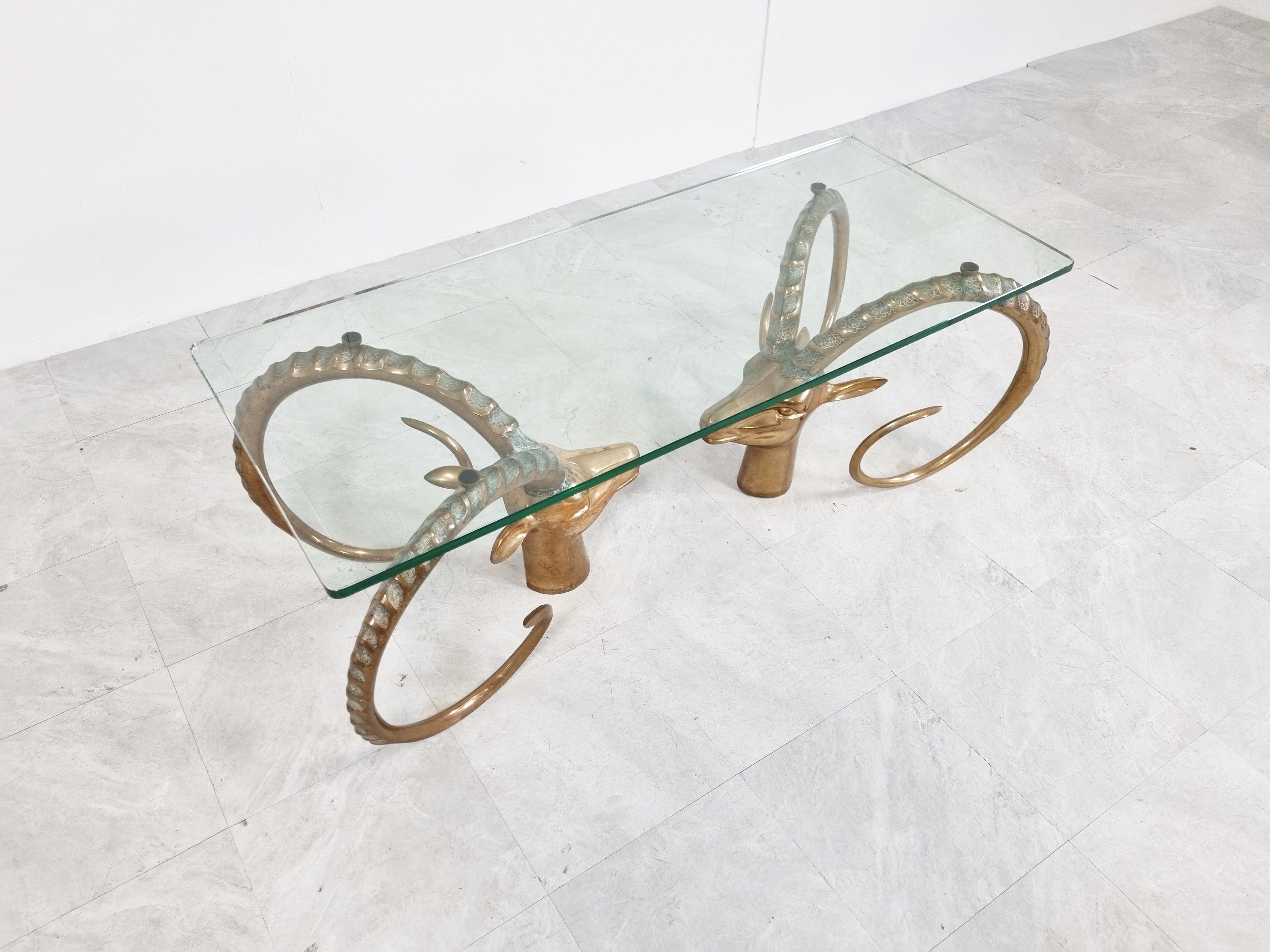 Seventies glam coffee table with a clear glass top supported by two solid brass ibex or antilopes sculptures.

Sometimes attributed to Alain Chervet

Very heavy quality 

1970s - France

Dimensions:
Table:
Height: 44cm/17.32